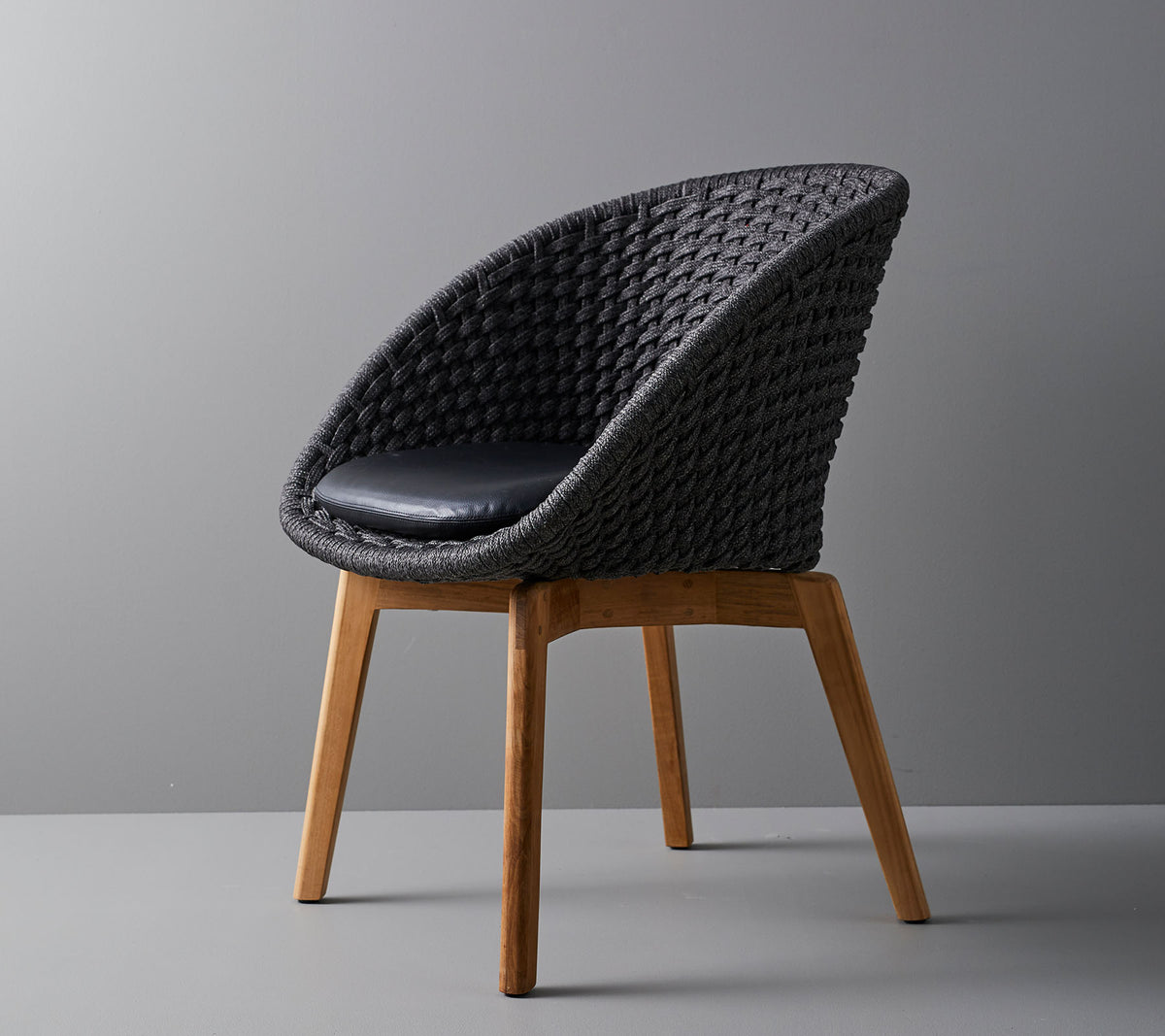 Stilig vevd stol med et komfortabelt pute, med glatte, avsmalnende treben og et moderne design som er passende for ulike omgivelser.