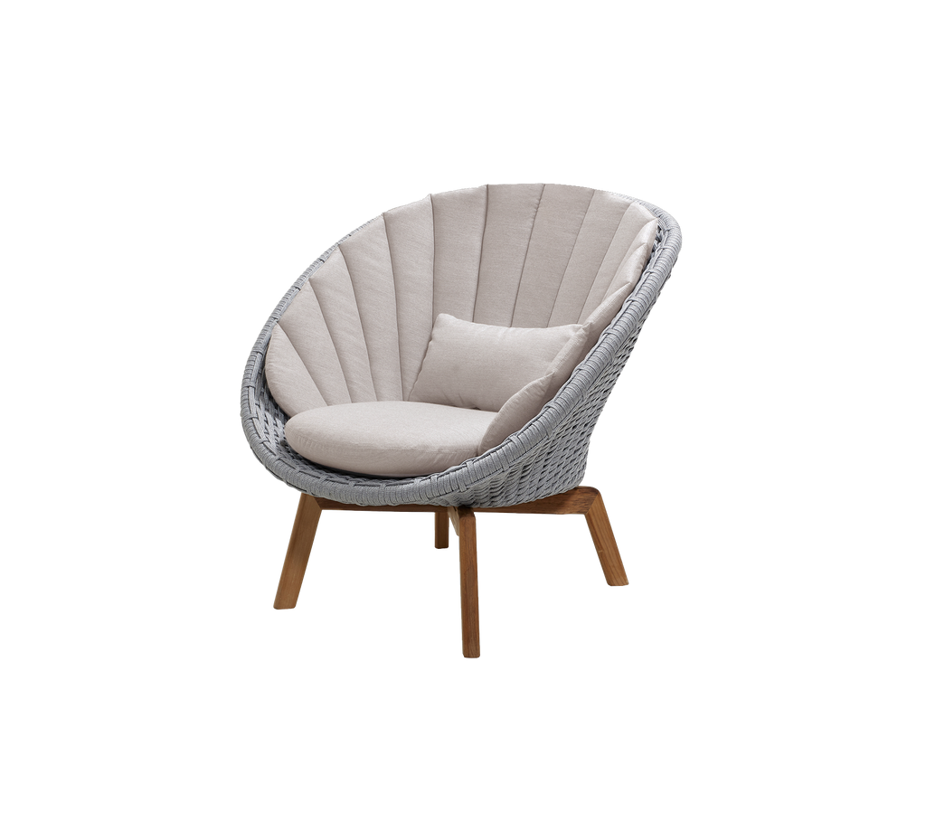 Moderne lys grå stol med sandfarget pute i en loungeinnstilling.