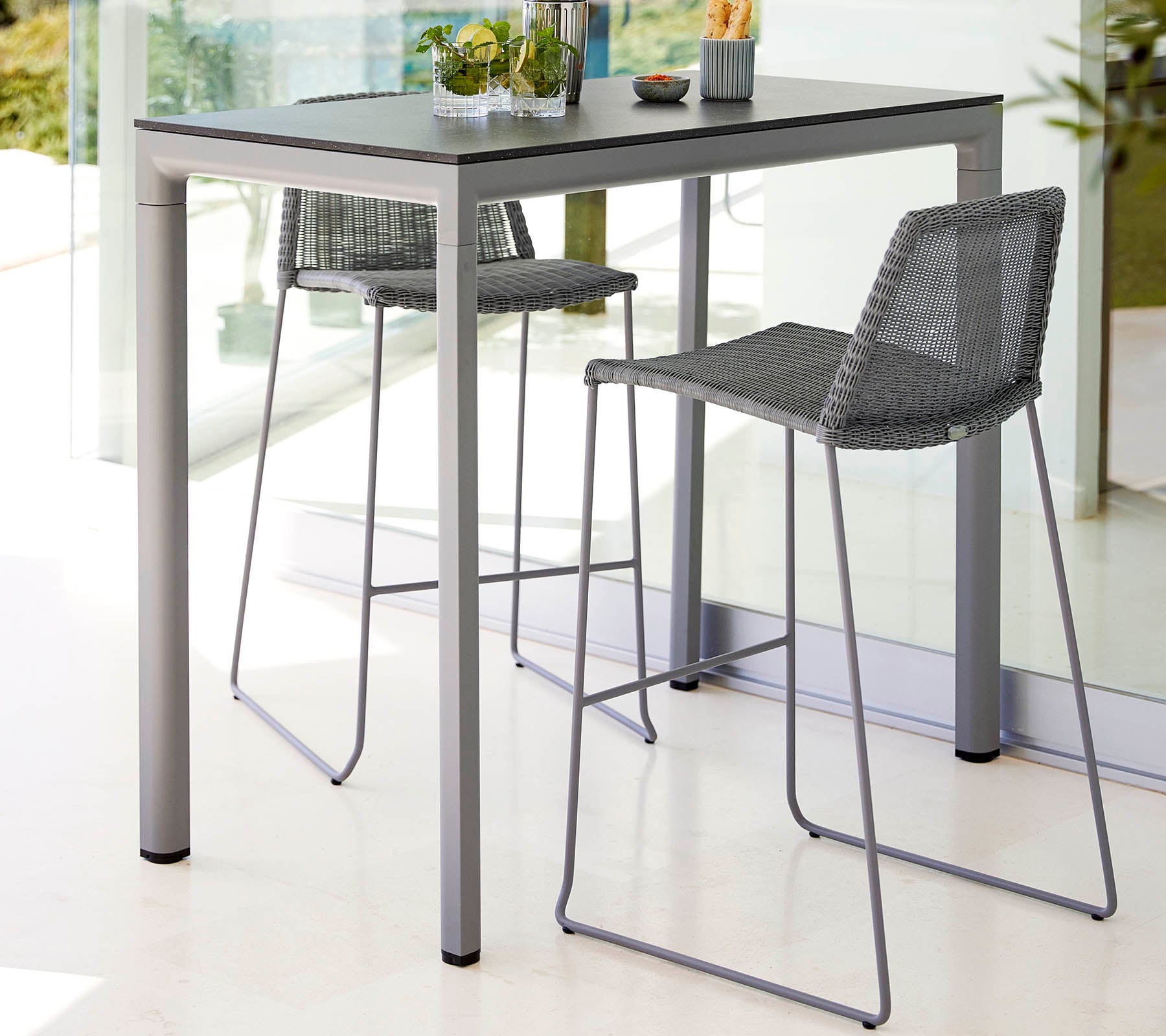 Et slankt bord med to høye barstoler, med et moderne design og lys fargepalett, komplementert av et lite planteinnslag.