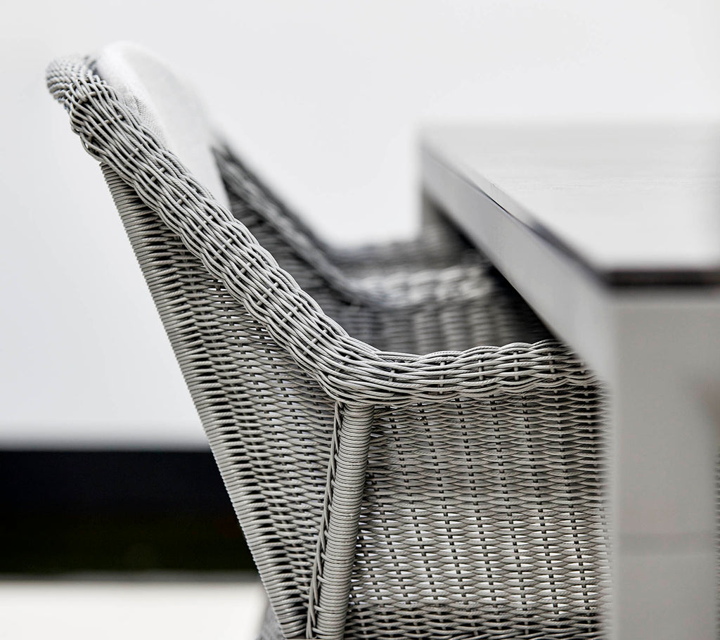 Et nærbilde av en stilig grå kurvstol ved siden av et strømlinjeformet bord, som viser moderne design og teksturer.