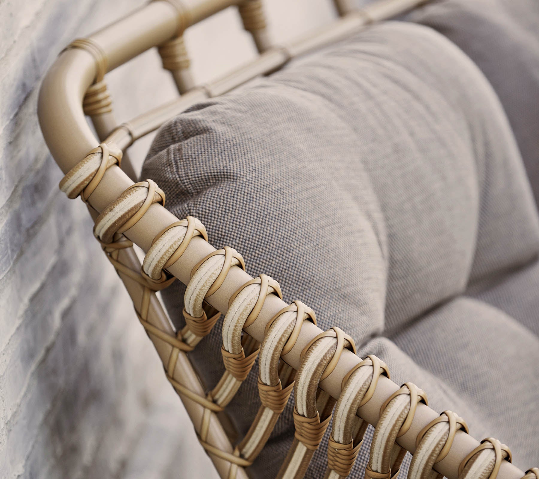 Stilig sittealternativ med en beige vevd ramme og myke grå puter, perfekt for å forbedre moderne interiør.