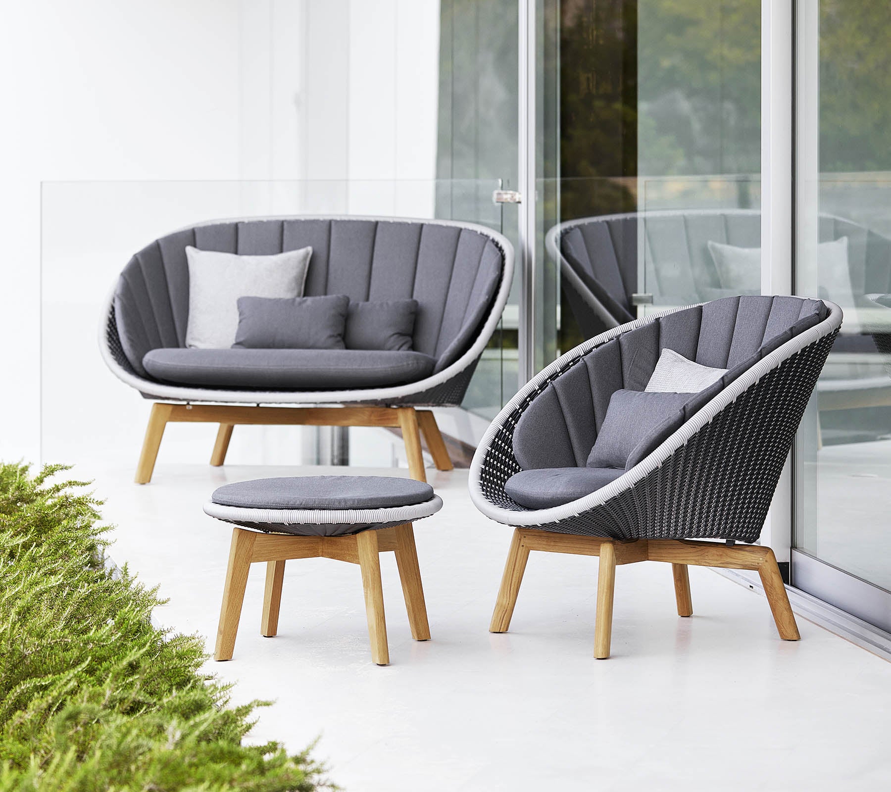 Stilig sittegruppe med en buet sofa, stol og rundt kaffebord, alt med moderne design og myke grå puter.