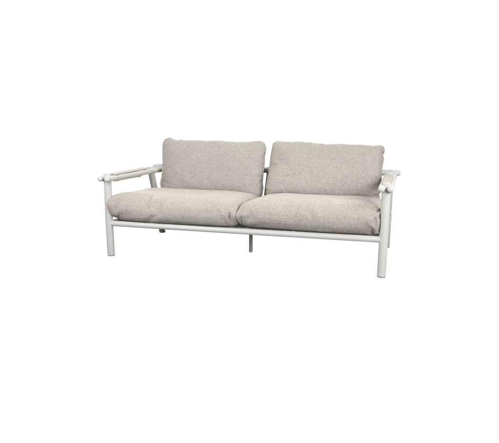 Moderne sofa med sandfargede puter og hvit ramme.