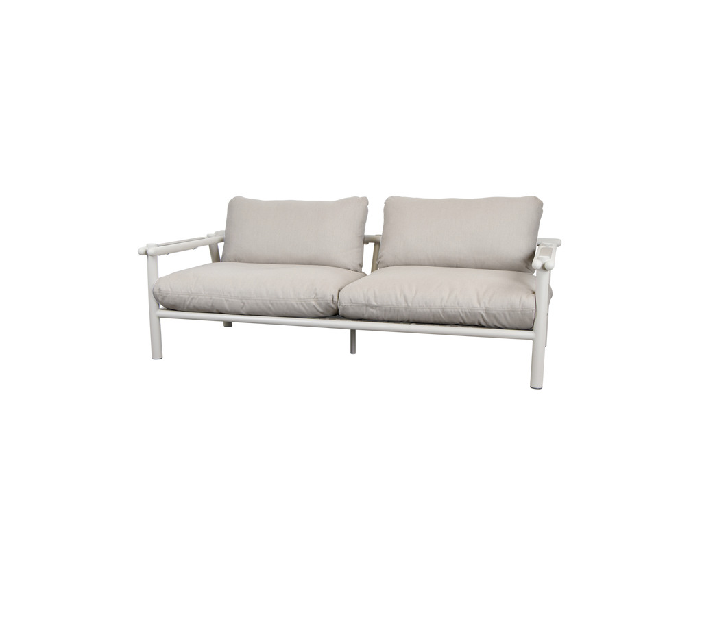 Moderne sofa med sandfargede puter og en lys ramme.