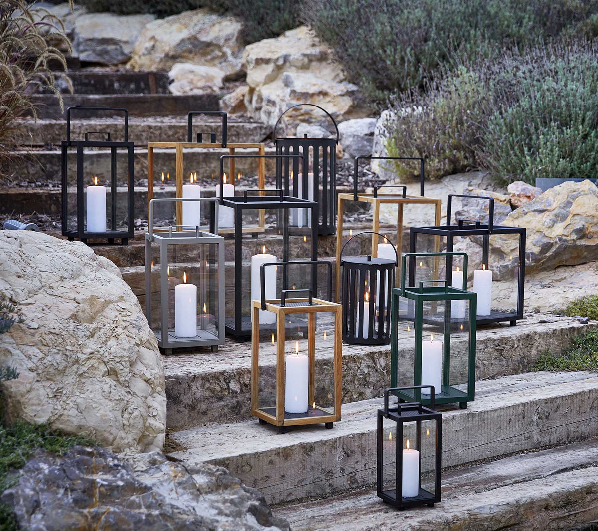Samling av dekorative lantern-er i forskjellige stiler og farger, med mykt stearinlyslys, kunstnerisk arrangert på steintrinn.