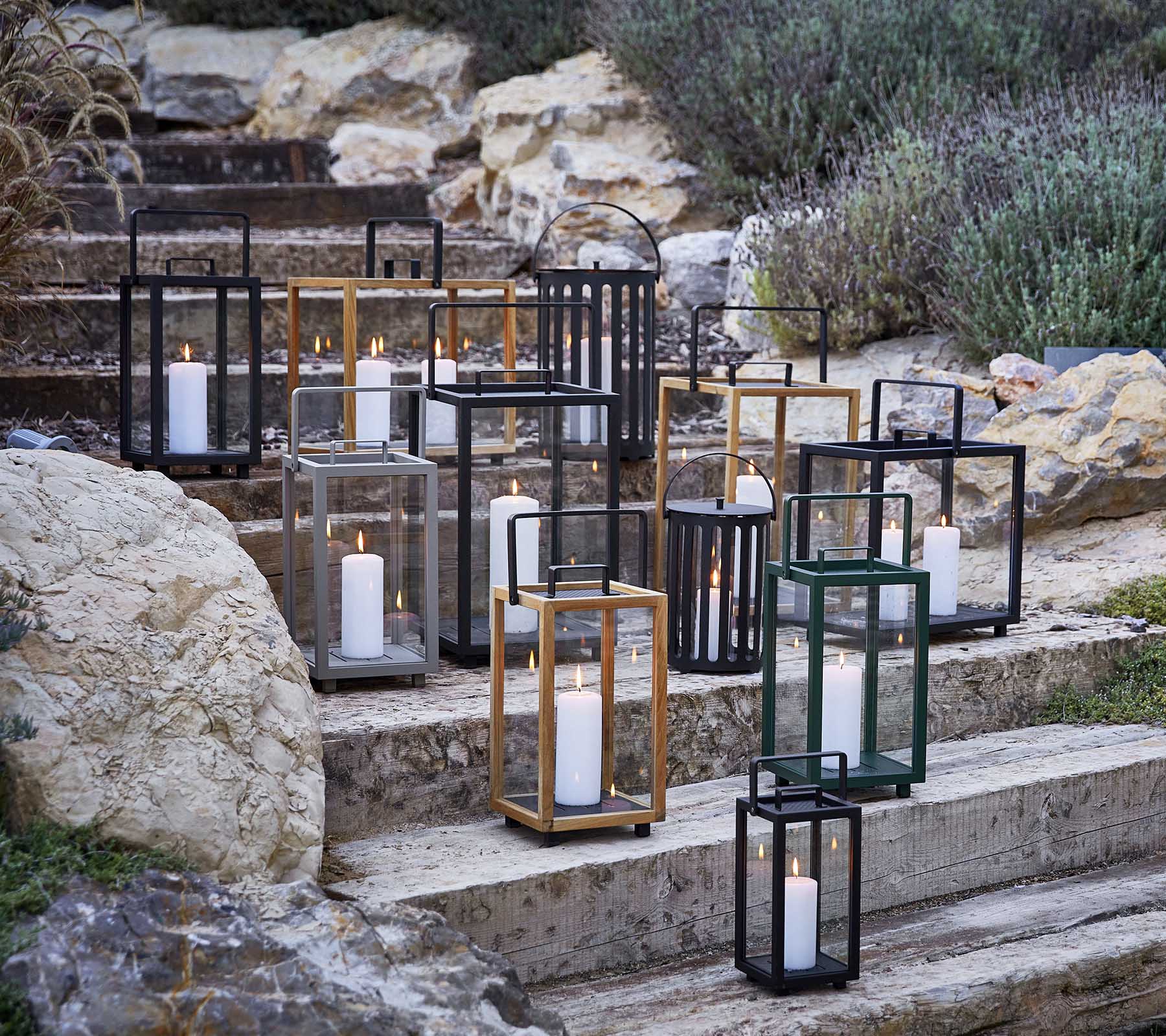 Samling av dekorative lantern-er i forskjellige stiler og farger, med mykt stearinlyslys, kunstnerisk arrangert på steintrinn.