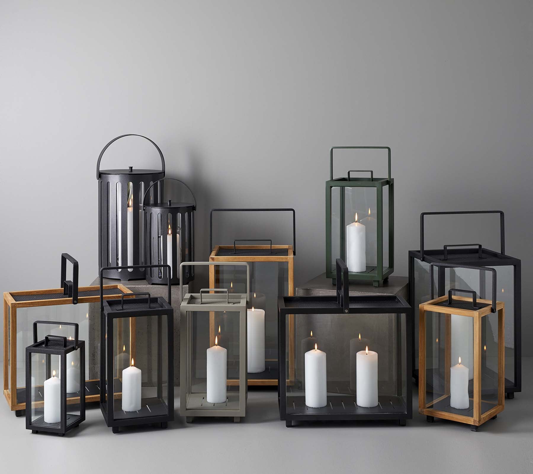 En samling av elegante lanterner i ulike størrelser og stiler, med stearinlys inni, arrangert sammen på en nøytral bakgrunn.