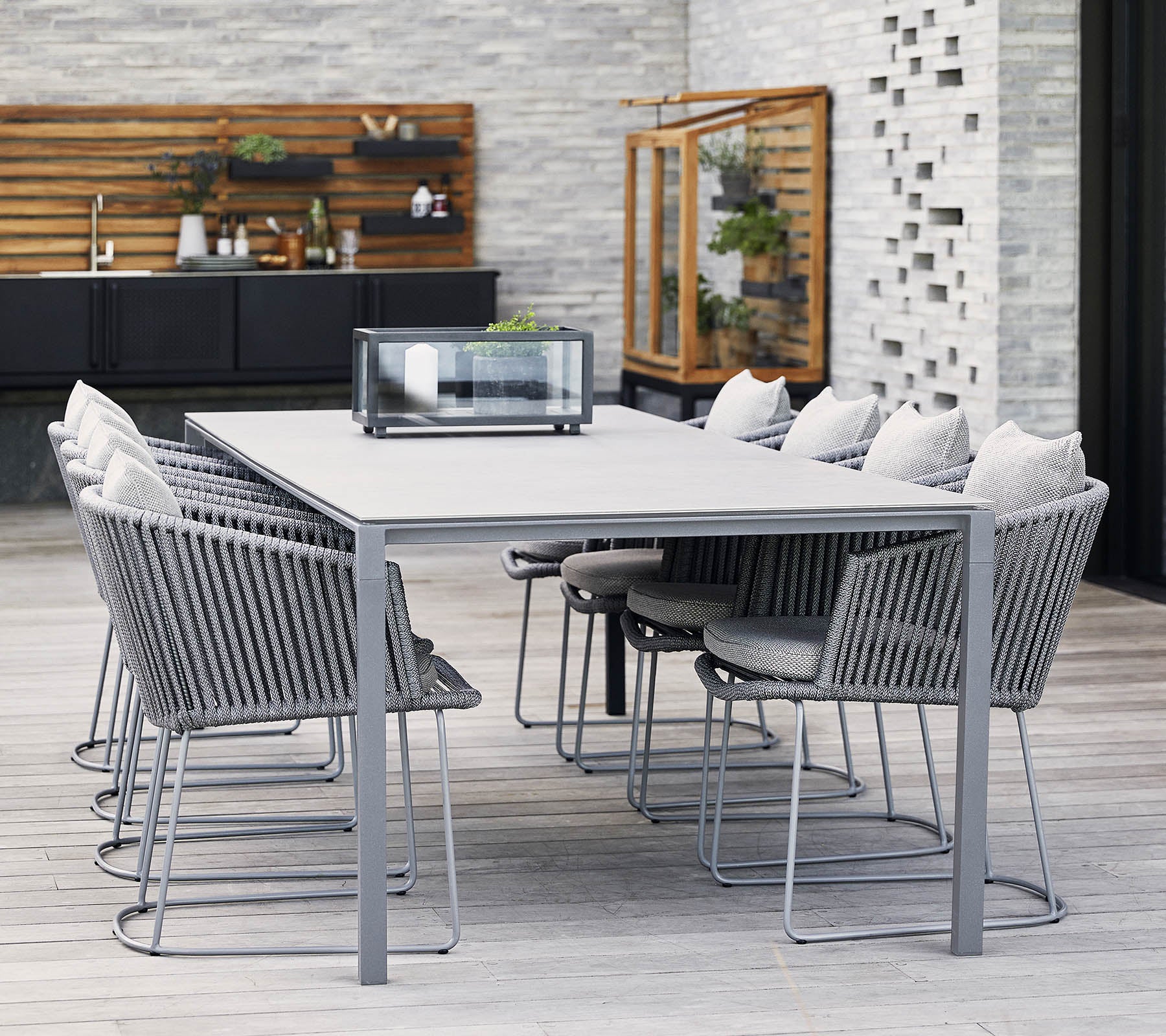 Et moderne spisebord med grå metallramme og komfortable stoler, med myke puter og minimalistisk design, perfekt for sammenkomster.