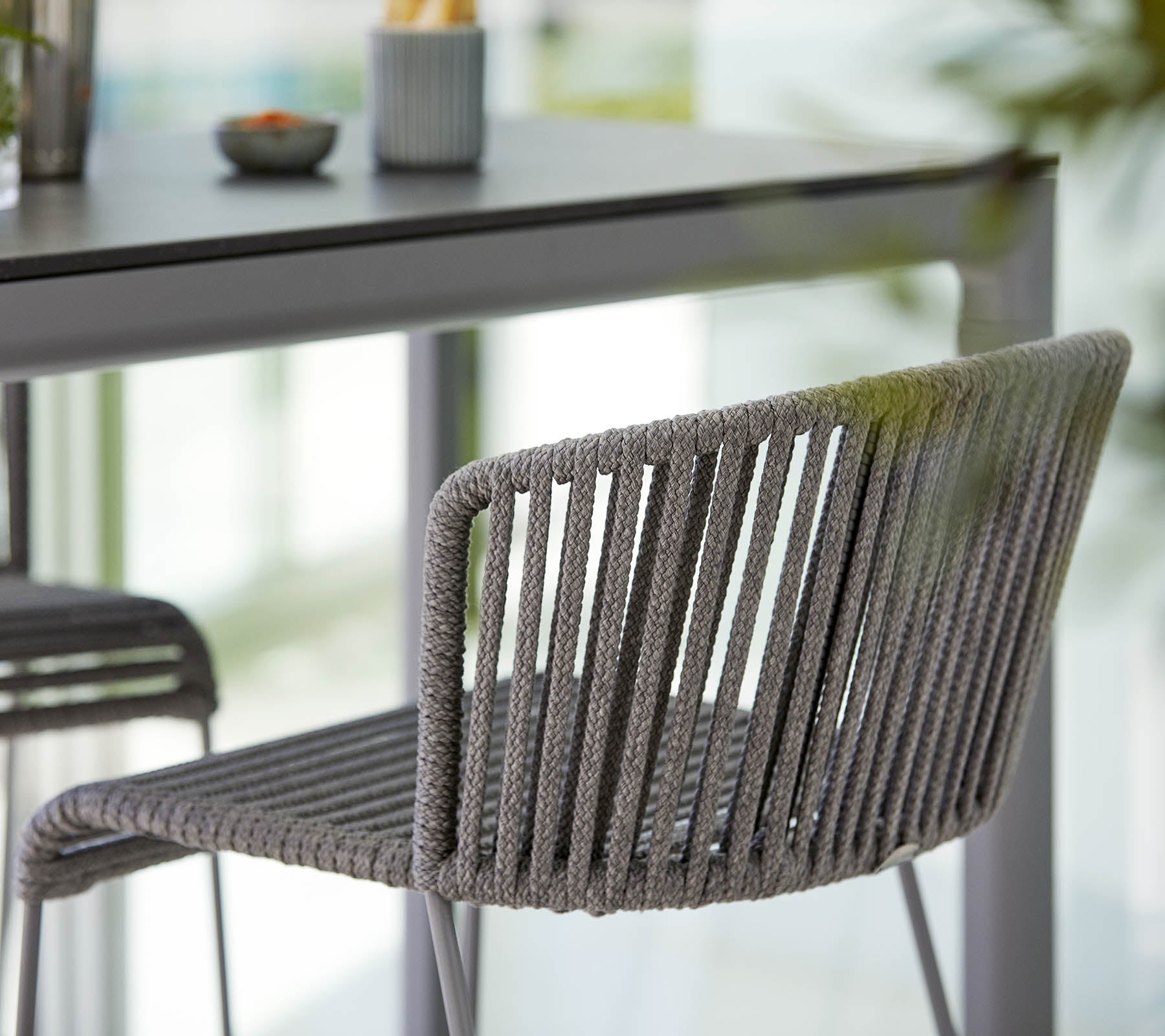 Stilig grå stol med et strømlinjeformet design, med vertikale striper og en moderne estetikk, plassert ved siden av et minimalistisk bord.