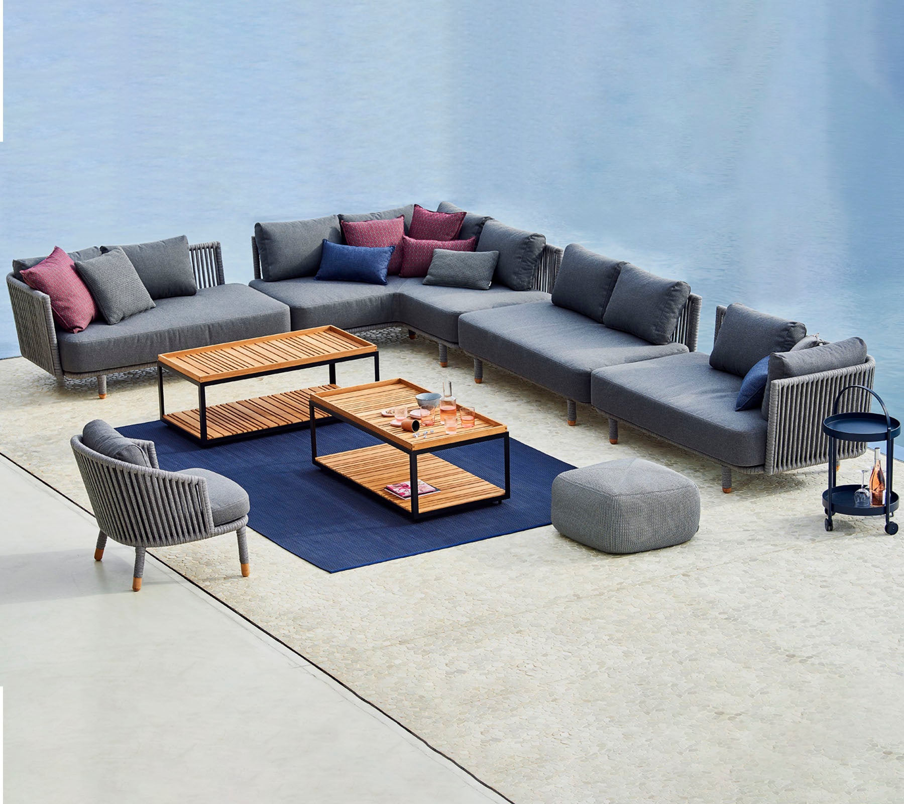 Moderne sittearrangement med en modulær grå sofa med fargerike puter, kaffebord og en matchende accentstol.