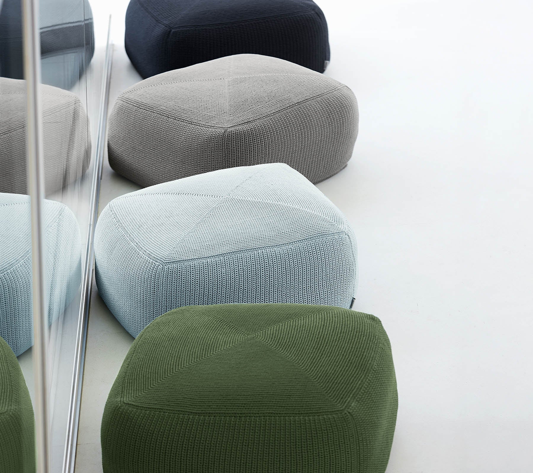 En samling av fargerike, teksturerte pouf i ulike nyanser, arrangert sammen, som reflekterer stilig og moderne design.