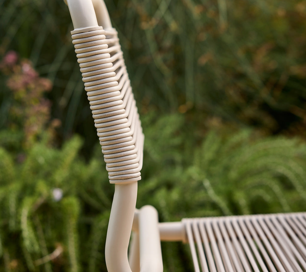 Beige stol delvis vist med en uskarp grønn bakgrunn.