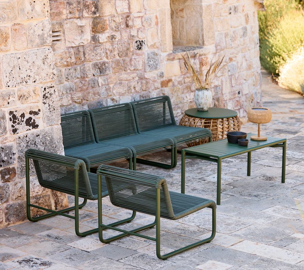 Moderne grønn sofa og stoler med et matchende bord i en uformell loungeinnstilling.