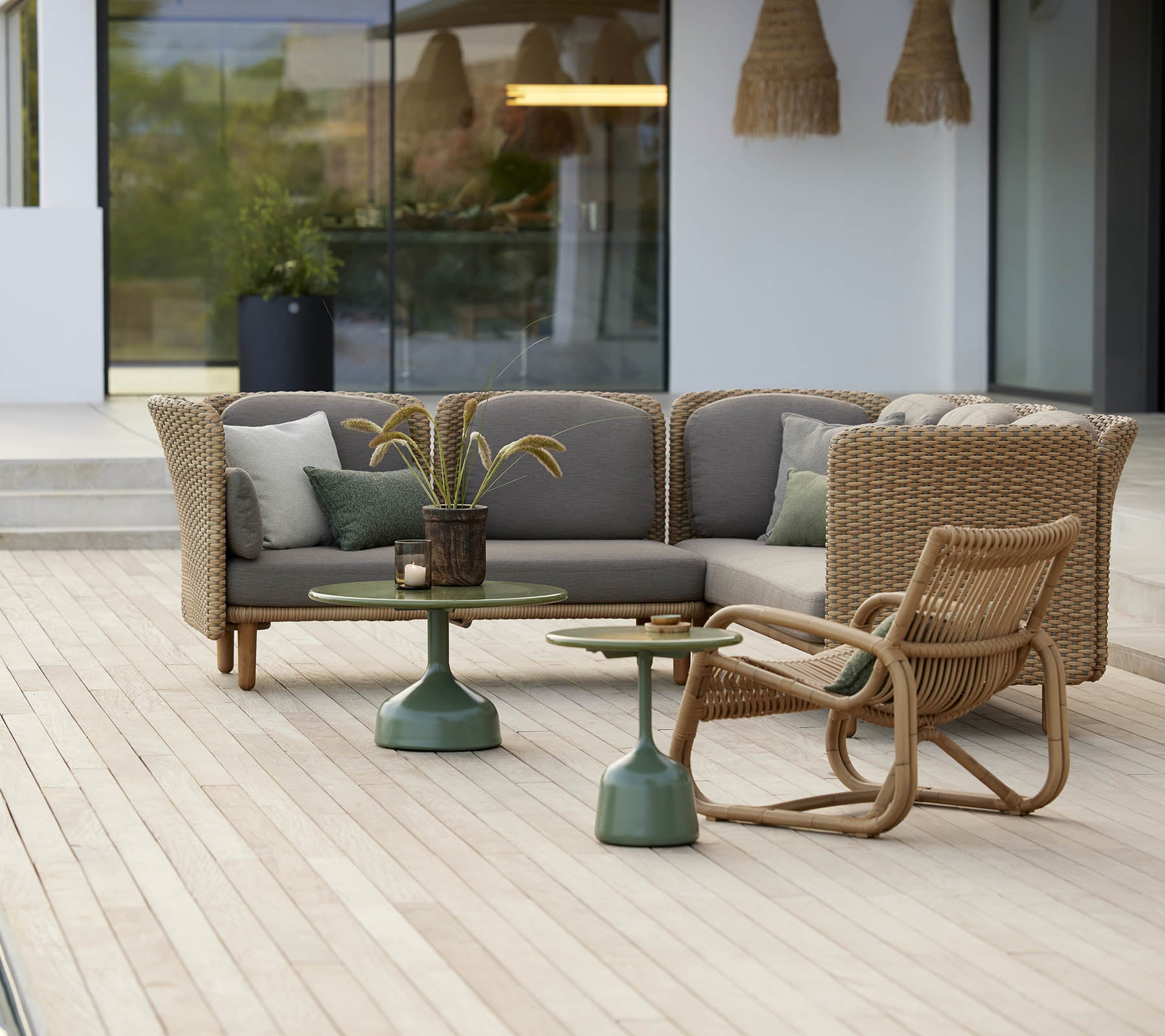 Stilig sitteområde med en buet loungestol og et bord med grønn base, komplementert av myke puter og dekorative elementer.