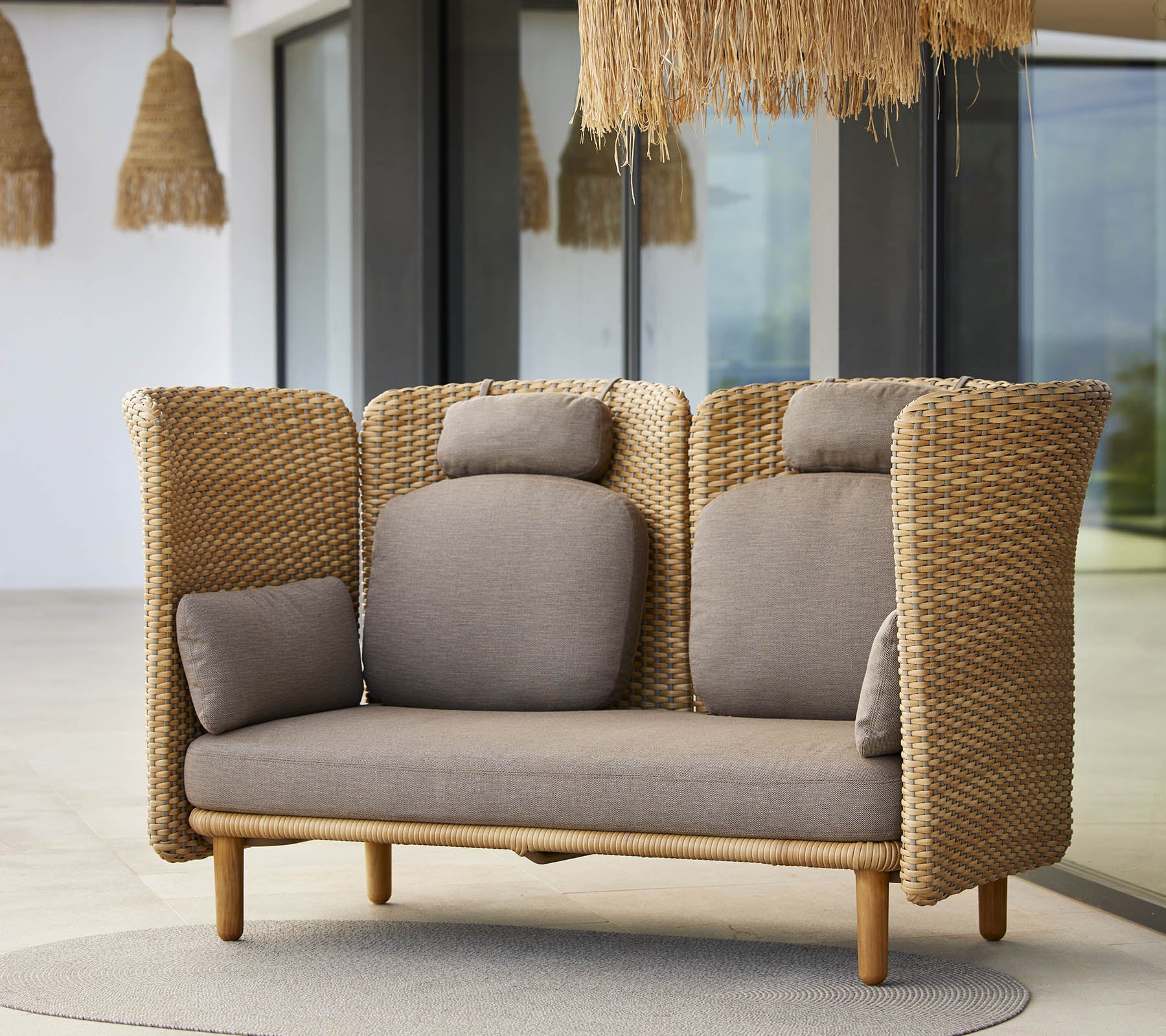 En stilfull lounge-sofa med vevde sider og myke puter, designet for komfort og avslapning. Ideell for moderne rom.