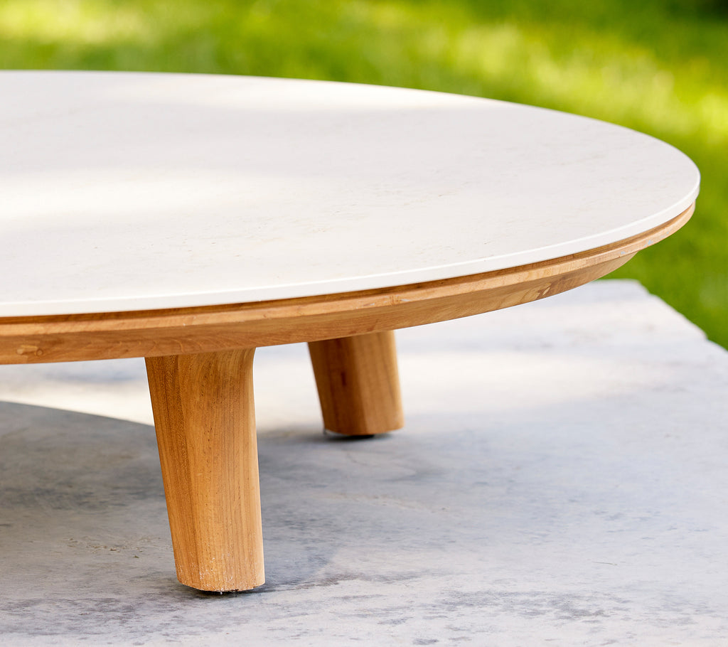 Nærbilde av et rundt sofabord med en jevn overflate og trebena, som fremhever den elegante designen og håndverket.