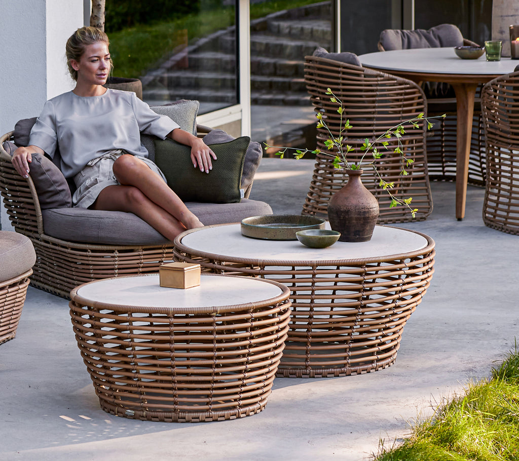 En sittende person slapper av ved medium og store flettede kaffebord, med en blanding av naturlige materialer og minimalistisk design.