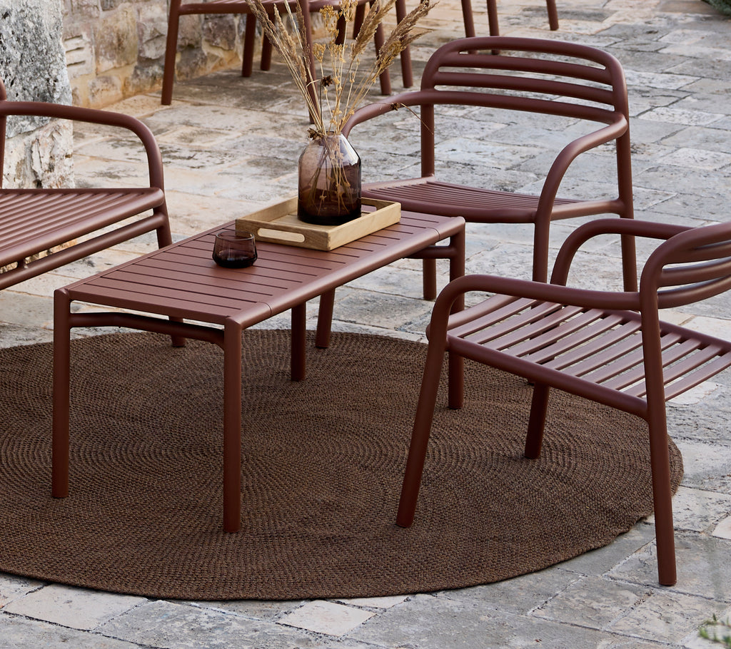 Minimalistisk brunt bord og stoler ordnet i en loungeinnstilling.