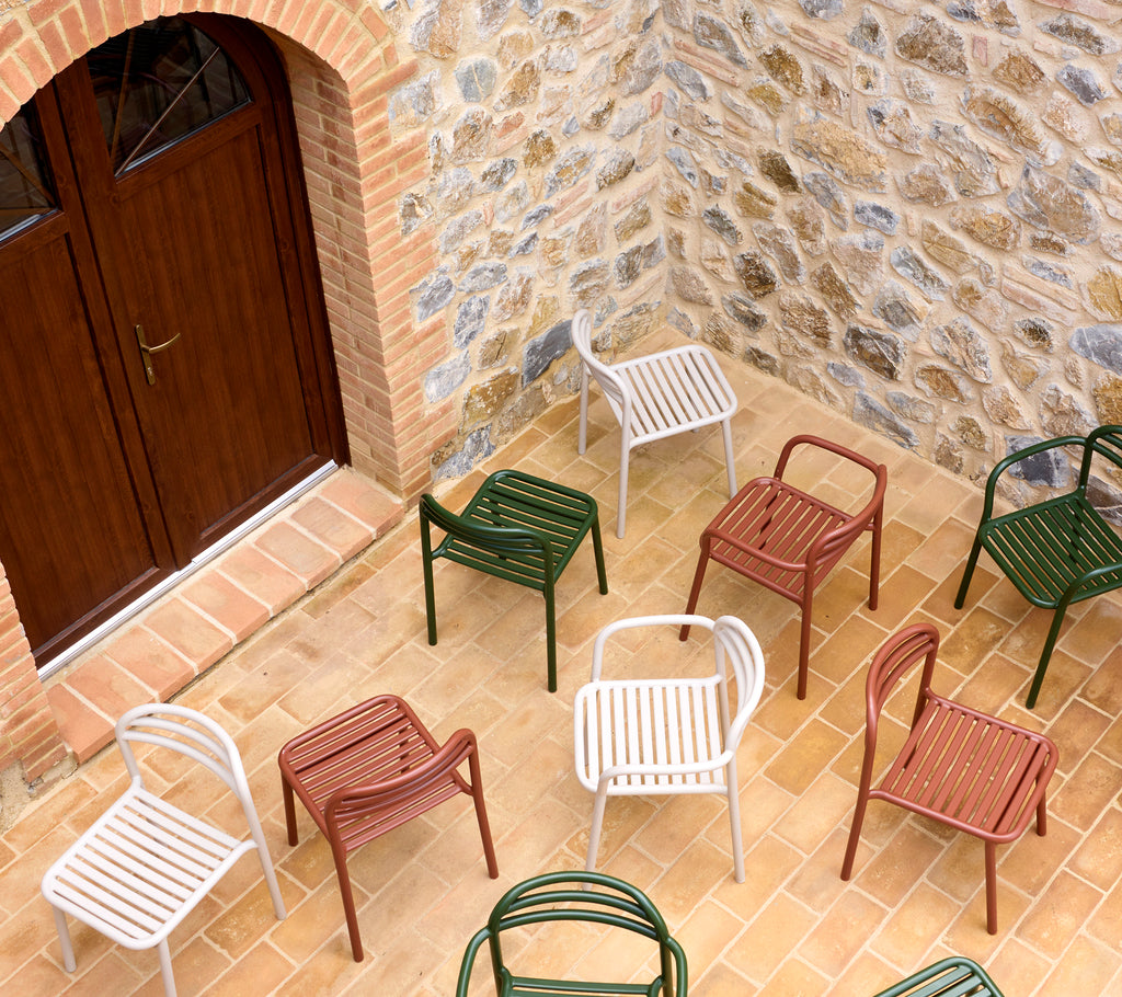 A variety of Bliss chairs in multiple colors arranged on a stone surface, showcasing modern design and vibrant hues.