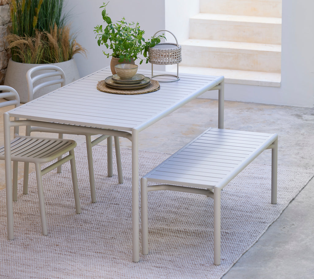 Moderne hvitt spisebord med matchende benk og stol i et minimalistisk miljø.