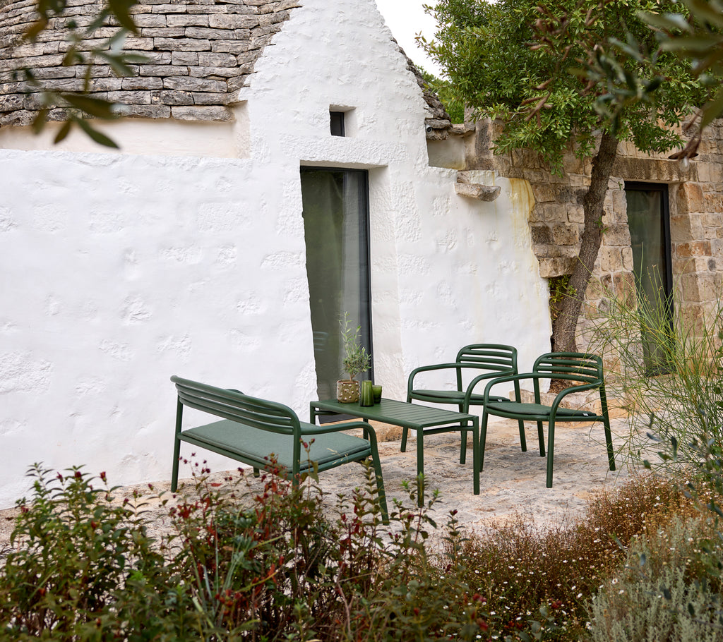 Grønn utemøbelsofa og stoler med et kaffebord i en koselig setting.