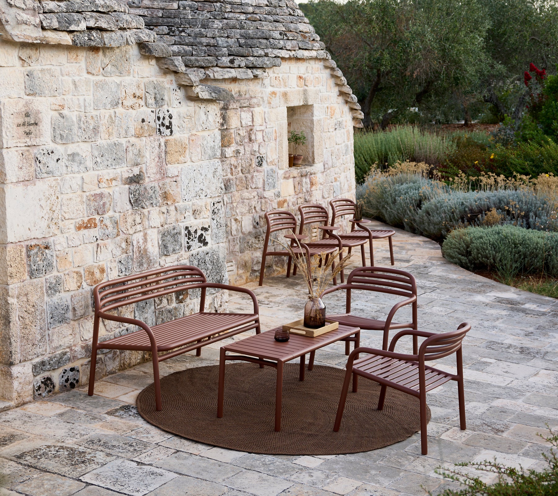 Brun utendørs sofa, stoler og bordsett i et moderne loungeområde.