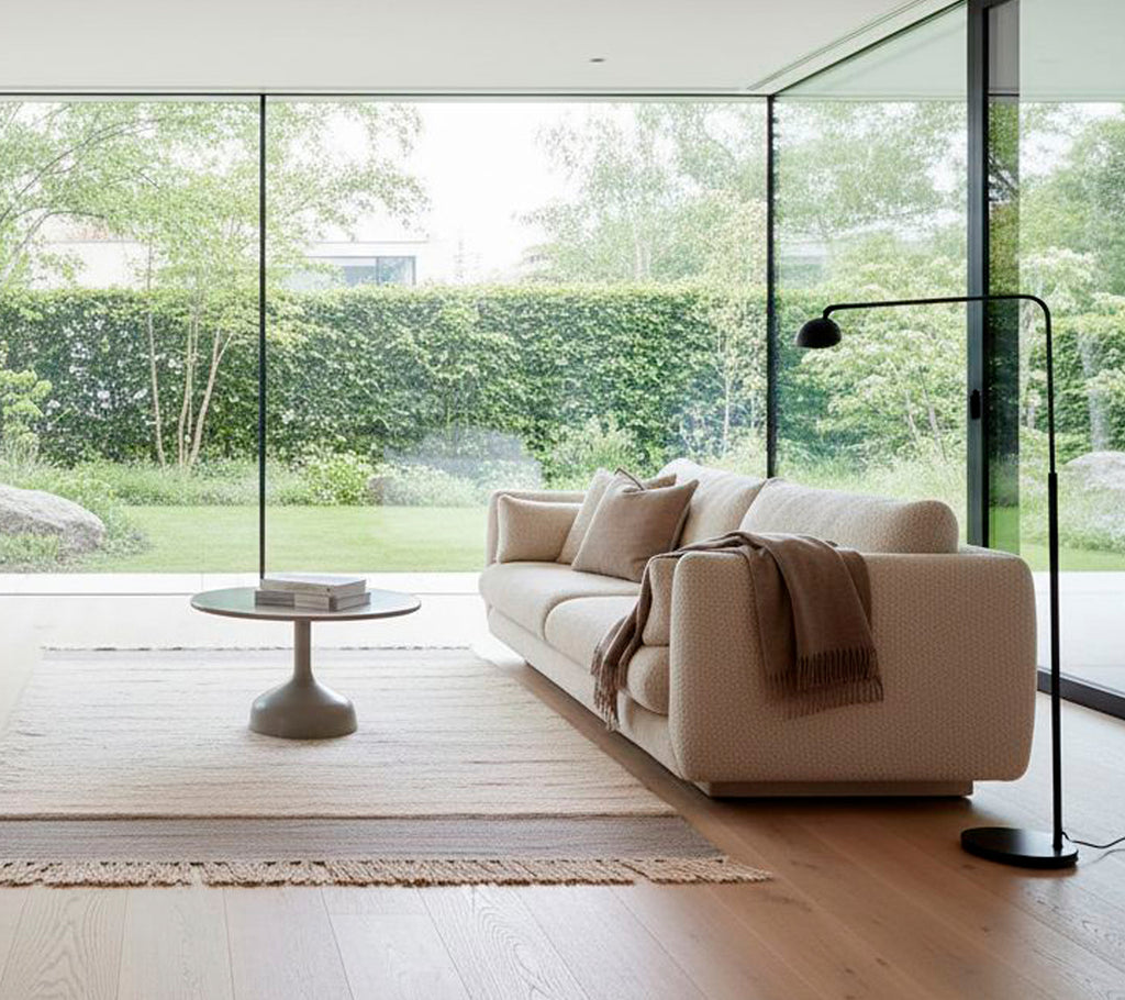 Moderne hvit sofa med en svart gulvlampe og rundt sofabord i en minimalistisk stue.