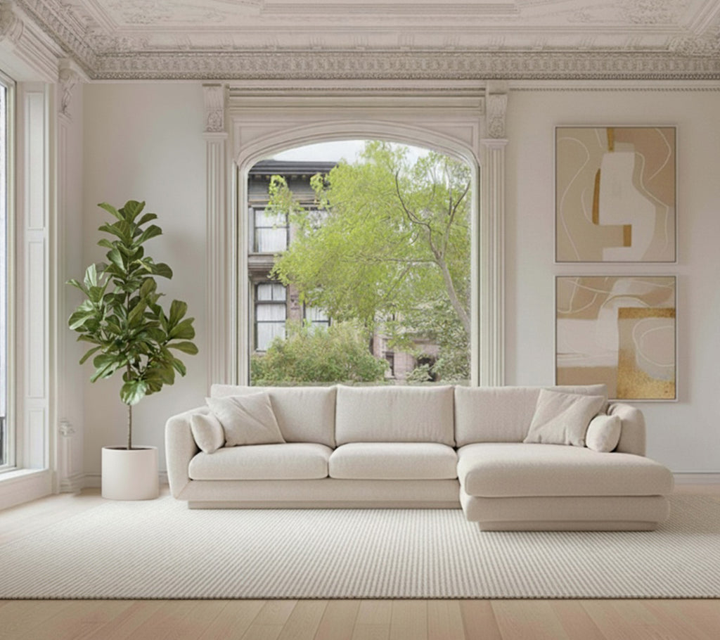 Beige seksjon sofa med en grønn plante og hvit teppe i et moderne loungeinnredning.