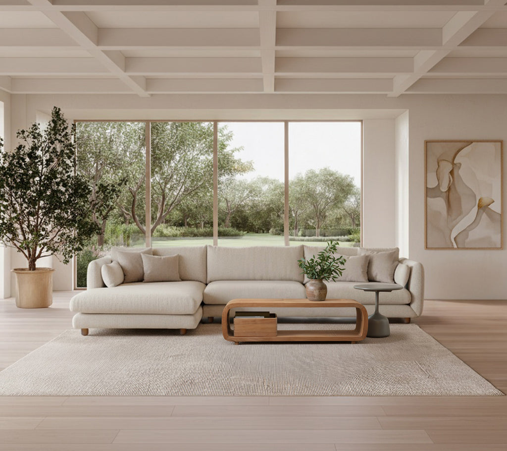 Lys grå sofa med trebord og stor plante i en moderne loungeinnstilling.