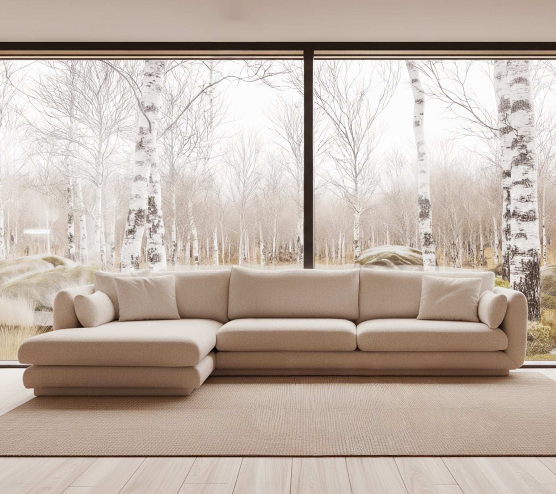Beige moderne sofa i en lys stueinnredning med store vinduer.