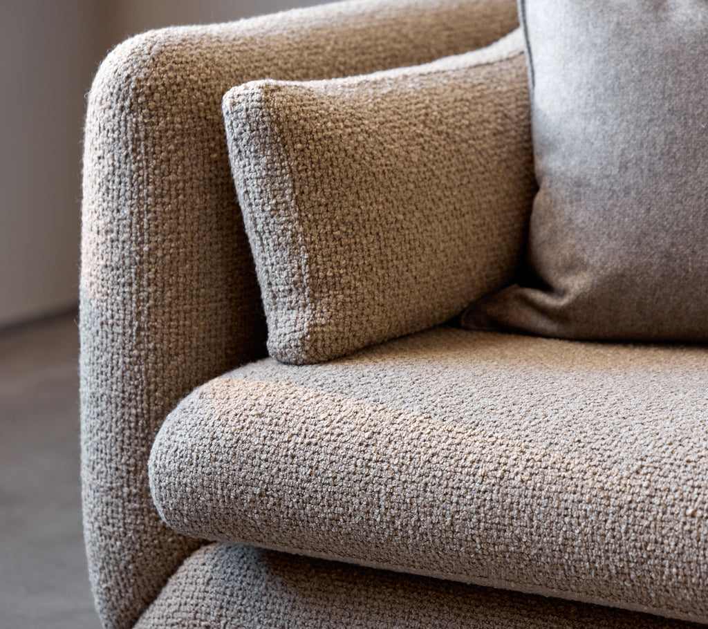 Nærbilde av et taupe Bloom-sofa-armlene, som viser dets teksturerte stoff og myke pute for ekstra komfort.