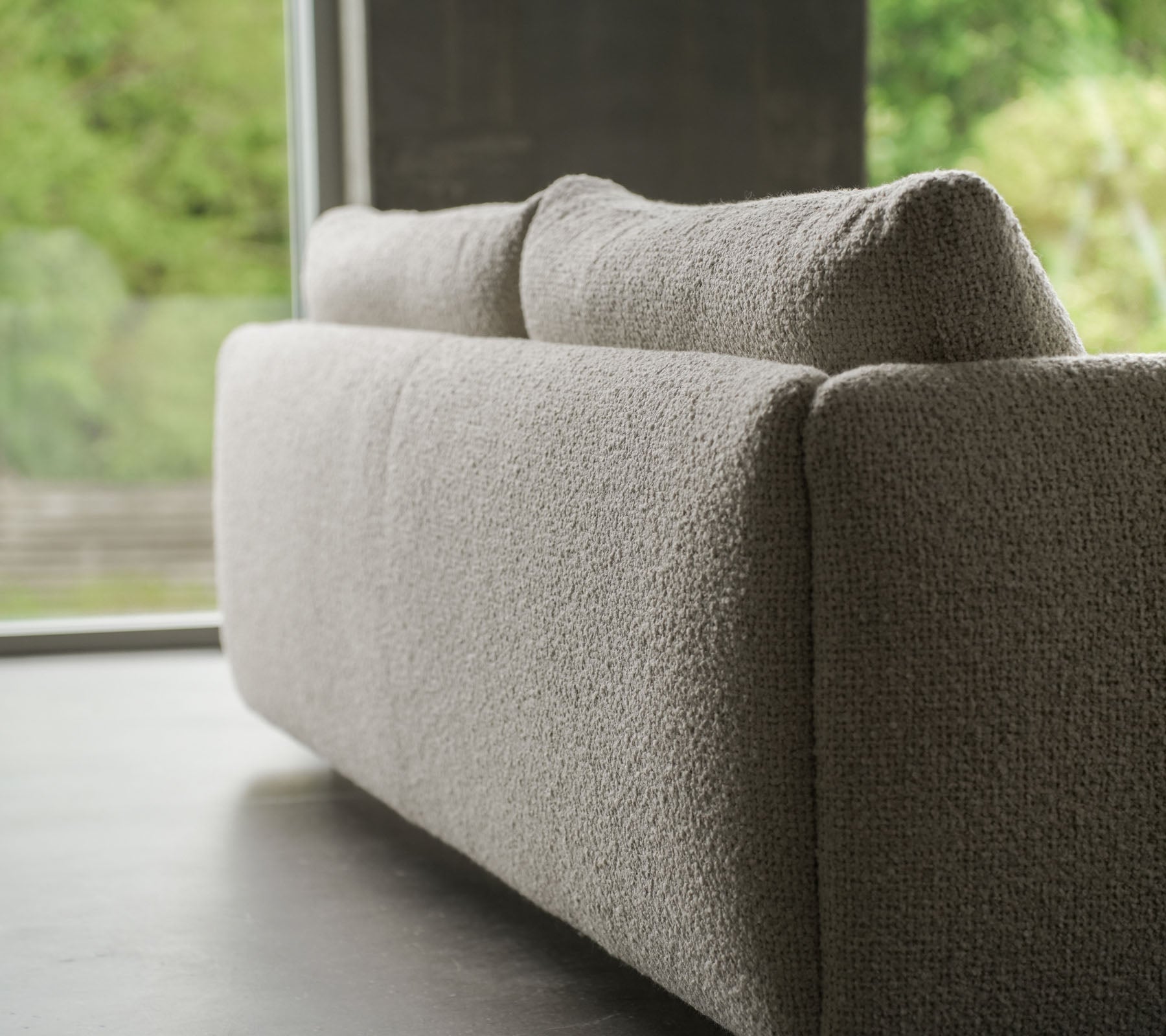 Samtidig sofa med en teksturert sandfarget stoff, aksentuert av elegante teakben, som viser Cane-line stil og myke puter.