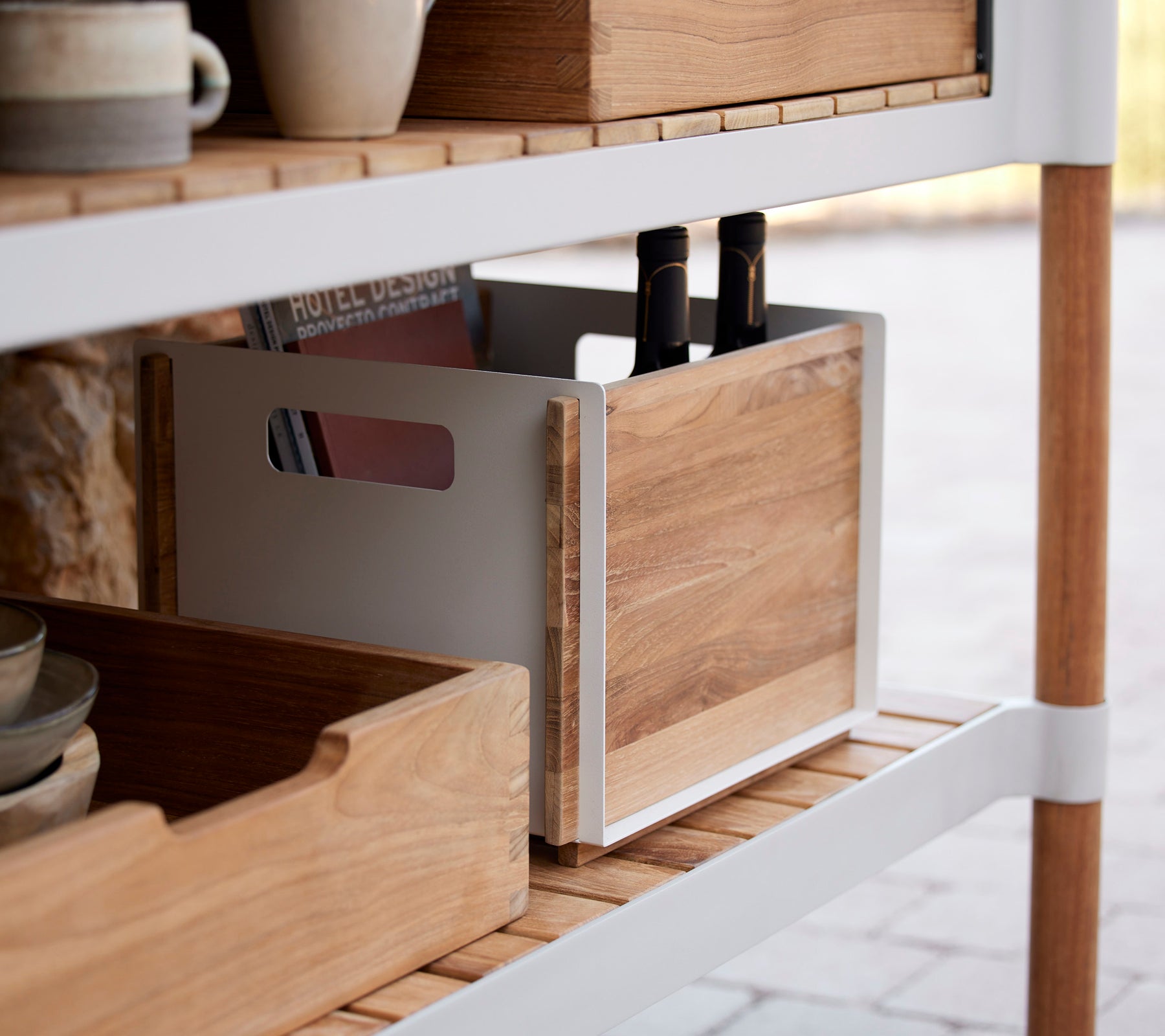 Wooden storage boxes on a shelf, one with kitchen utensils inside, featuring a minimalist design and natural finishes.