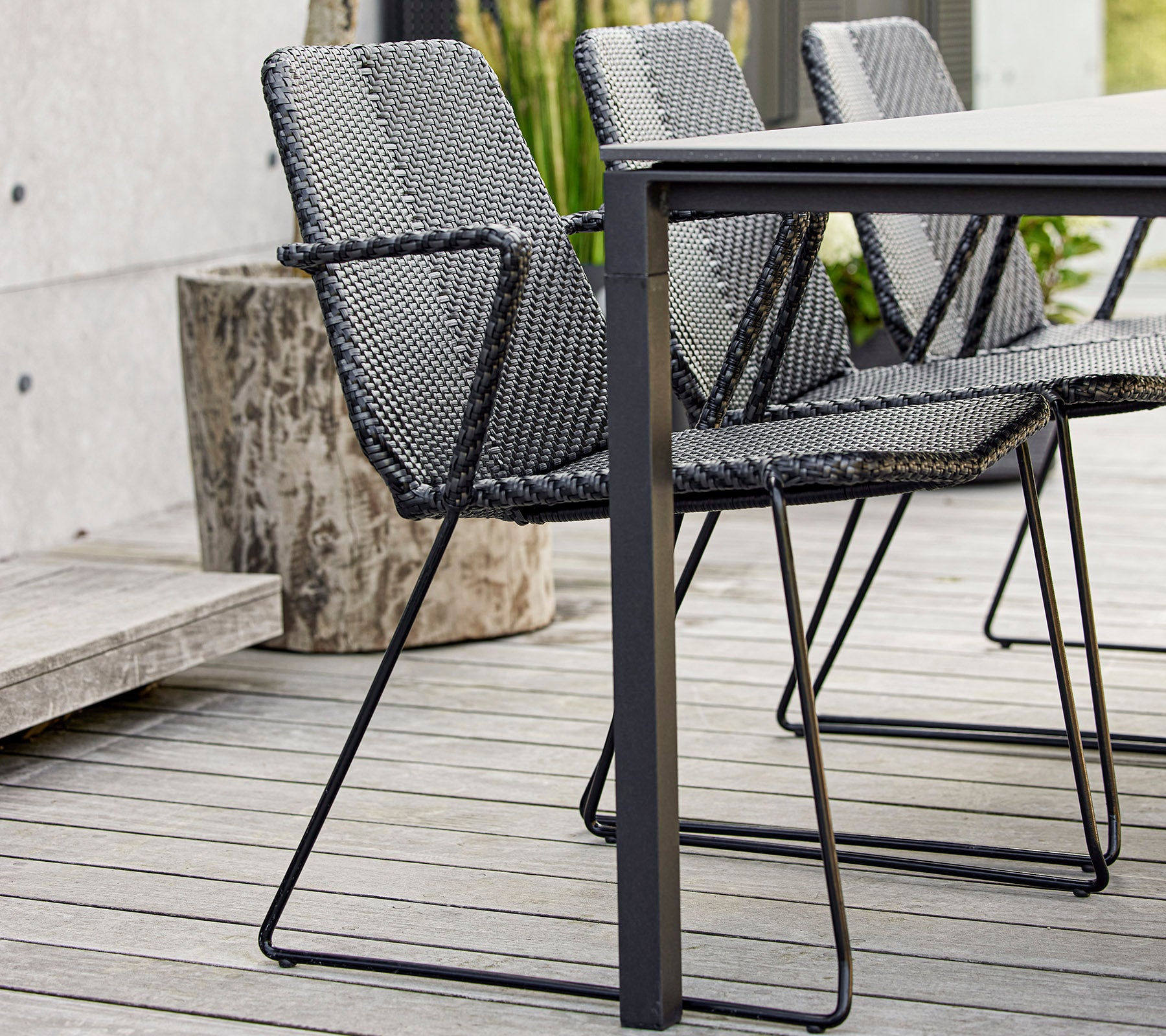 Et sett med moderne svarte flettede stoler plassert rundt et strømlinjeformet bord, som viser moderne design og håndverk.