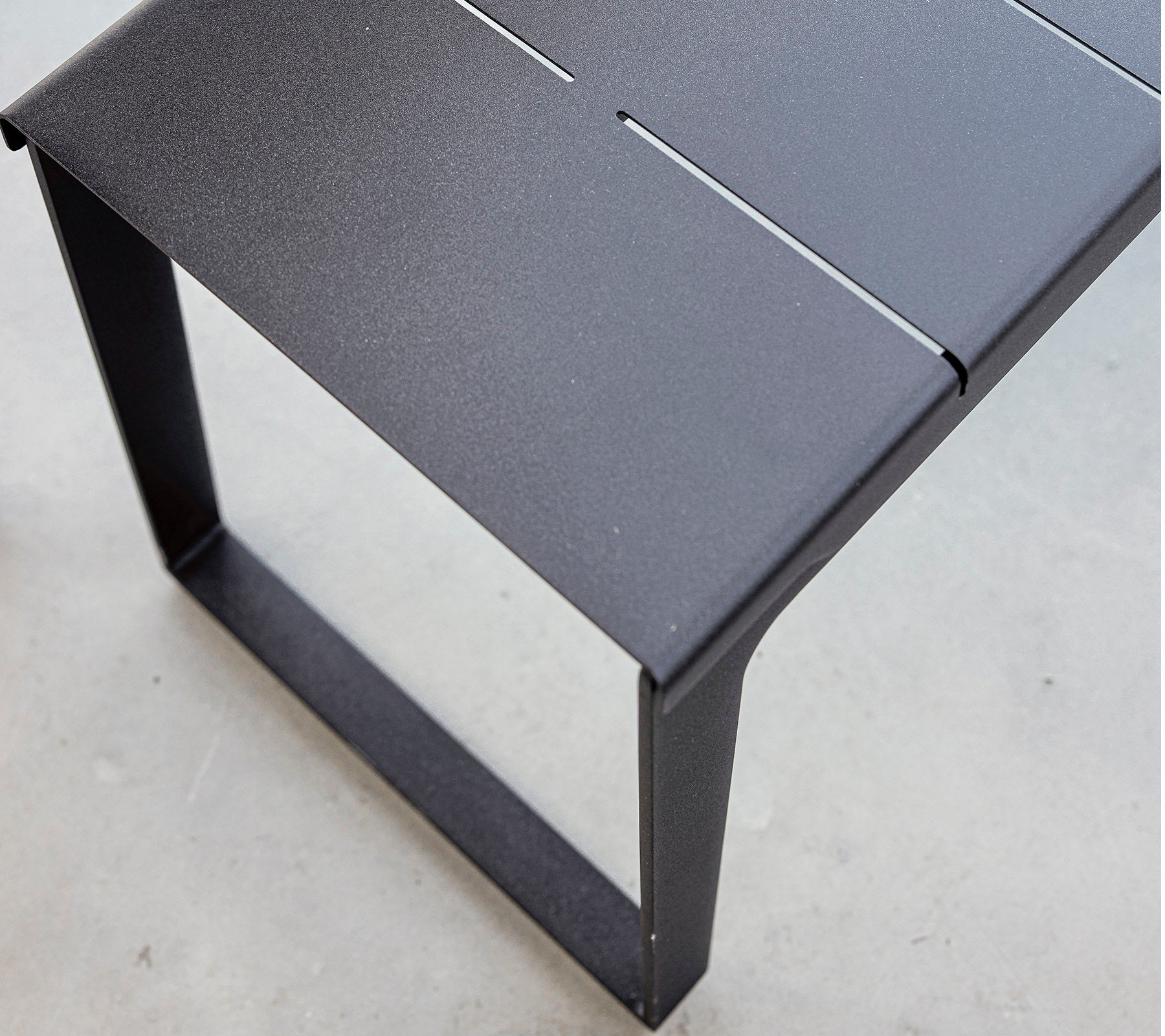 Svart metalbord med et stilrent design og minimalistisk estetikk, med en lamellert topp og solid ramme. Ideell for moderne omgivelser.