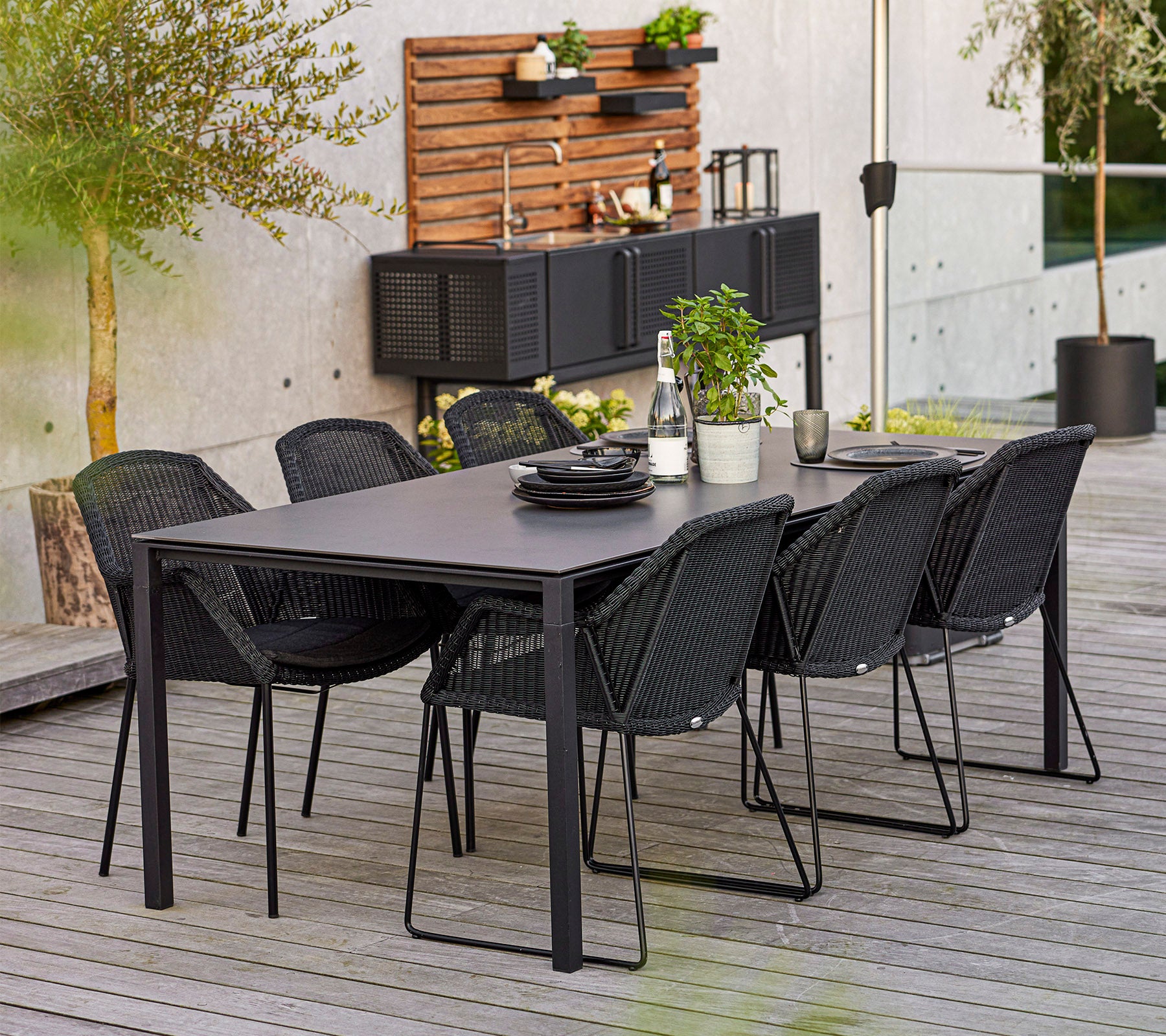 Et moderne spisestue-set med et rektangulært bord og seks stilige stoler, komplettert med dekorative planter og servise.
