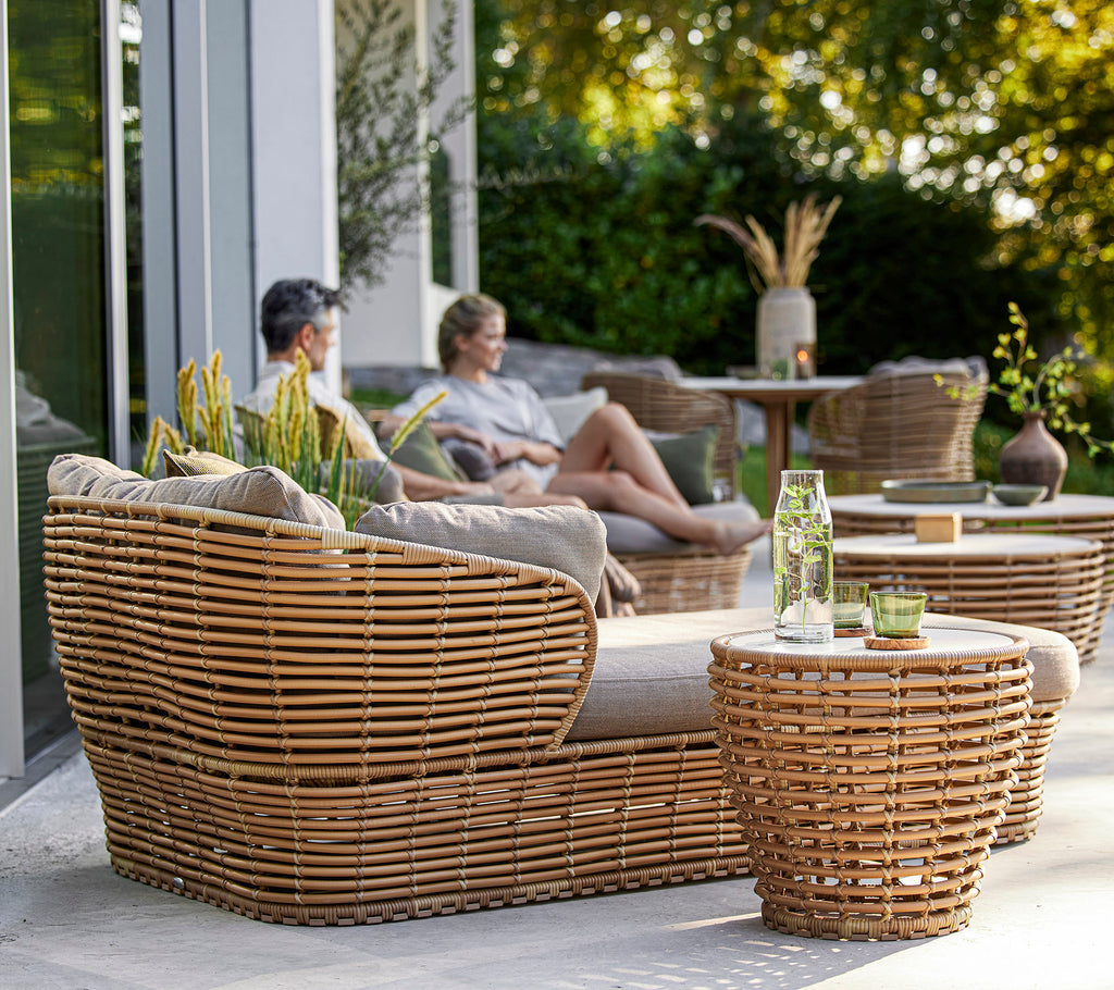 Stilig vevd møbelsett med et koselig sitteområde og bord, complementert med dekorative planter og en avslappet atmosfære.