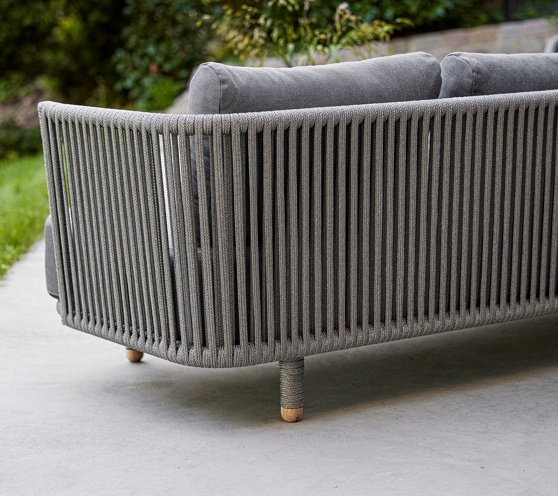 Sleek, moderne grå sofa med vertikal lamelldesign og ben i tre, ideell for moderne utendørs eller innendørs rom.