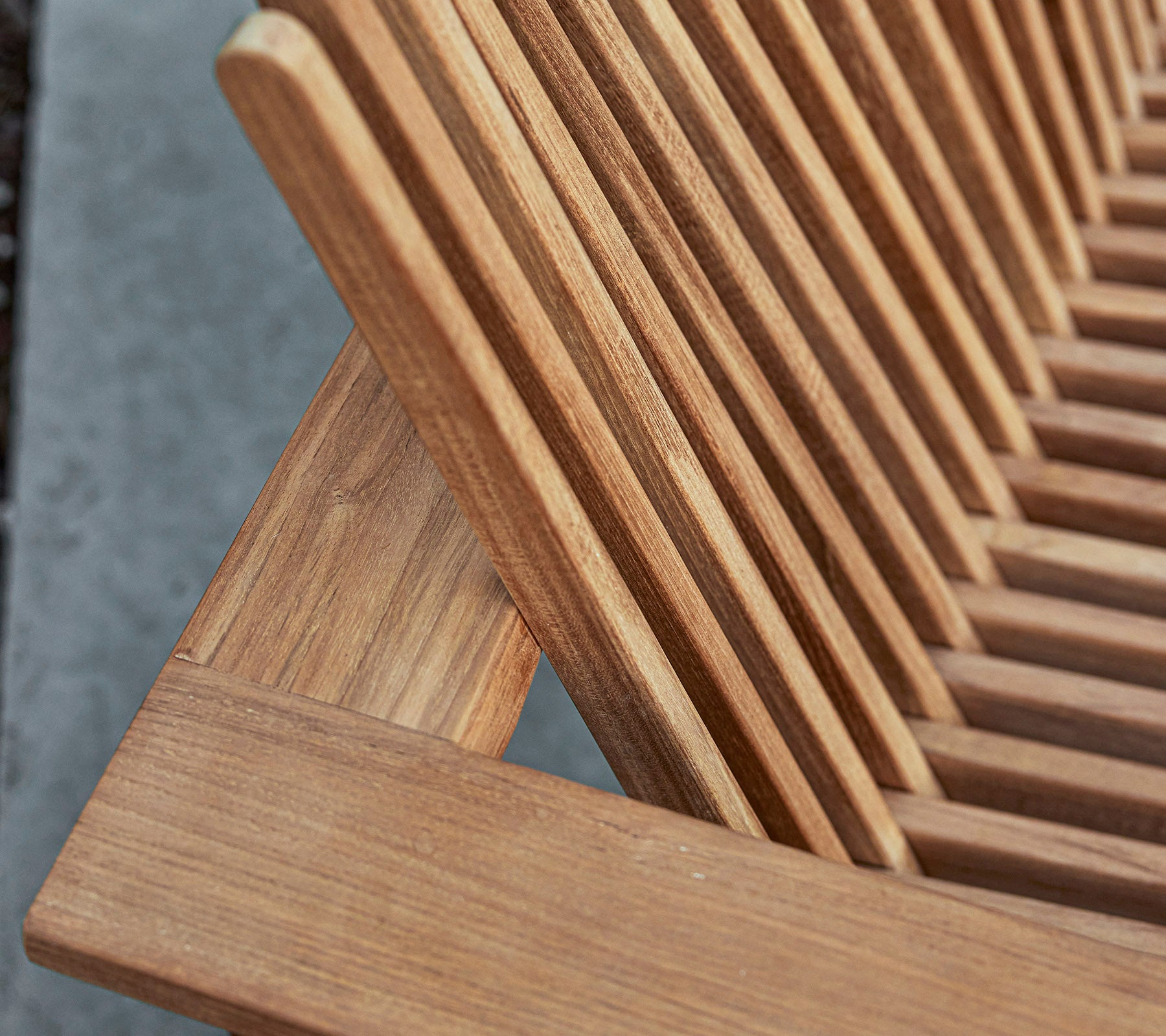 Nærbilde av et møbel i tre med lamelldesign, som viser den naturlige åre og håndverksdetaljer.