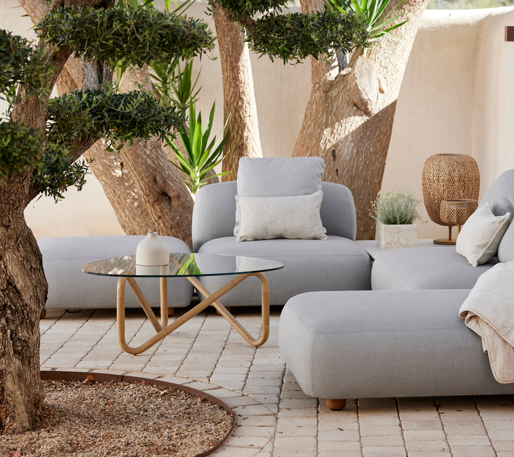 Moderne loungeområde med en grå sofa, hvit pute og glassbord.