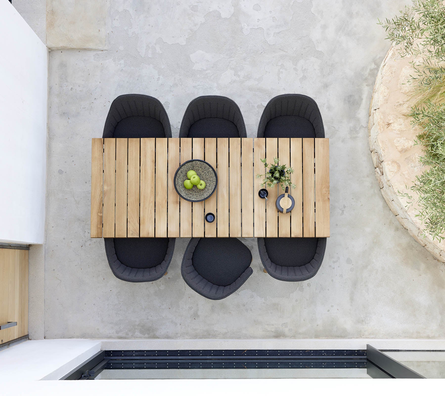 Stilig tre spisebord med fire svarte stoler, med en skål med grønne frukter og dekorative planter for et moderne preg.