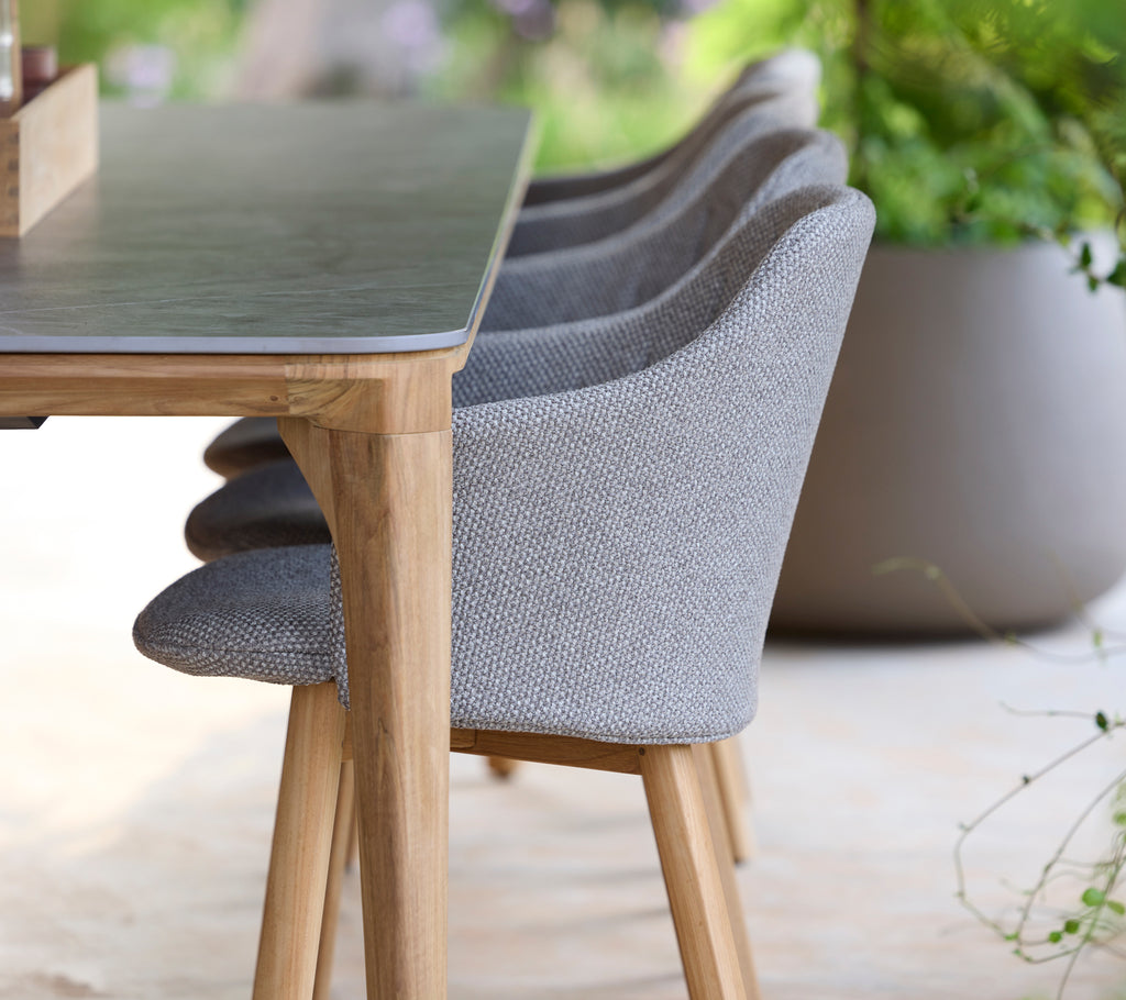 Moderne grå stol og bord i en rolig utendørs setting.