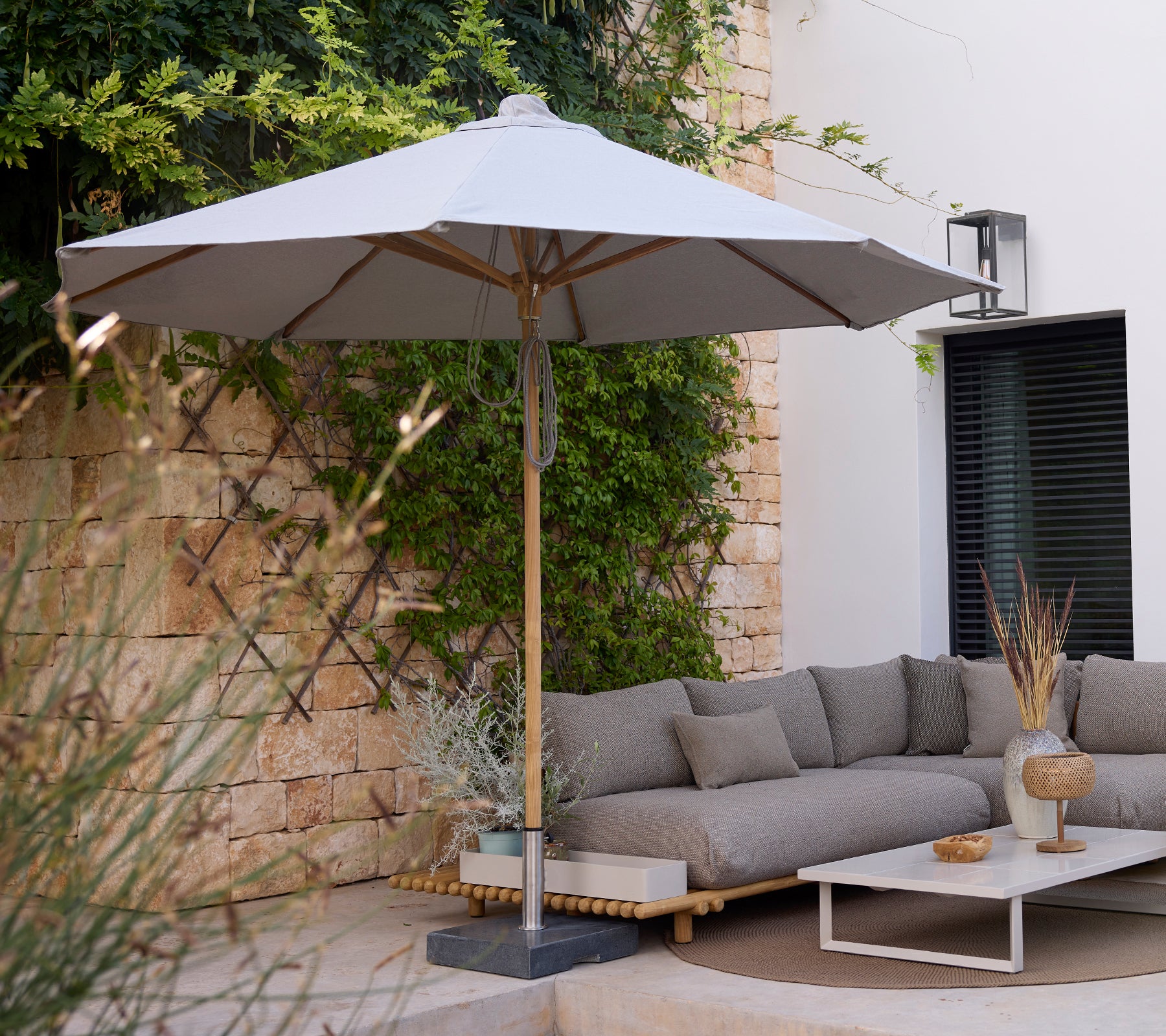 Moderne loungeområde med en grå sofa, hvit bord og grå paraply.