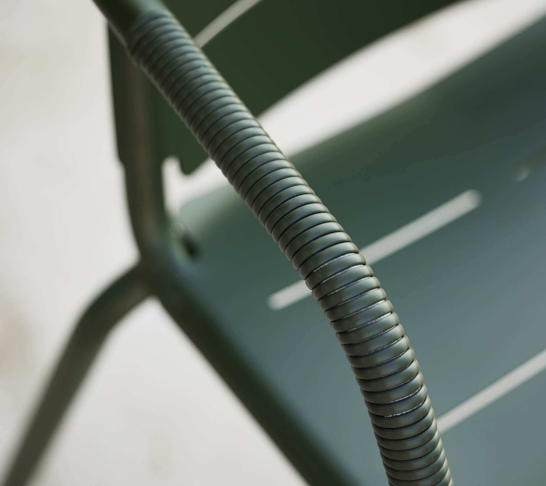 Nærbilde av en grønn Copenhagen-stol, som fremhever dens buede armlene og elegante design med subtile spalter på setet.