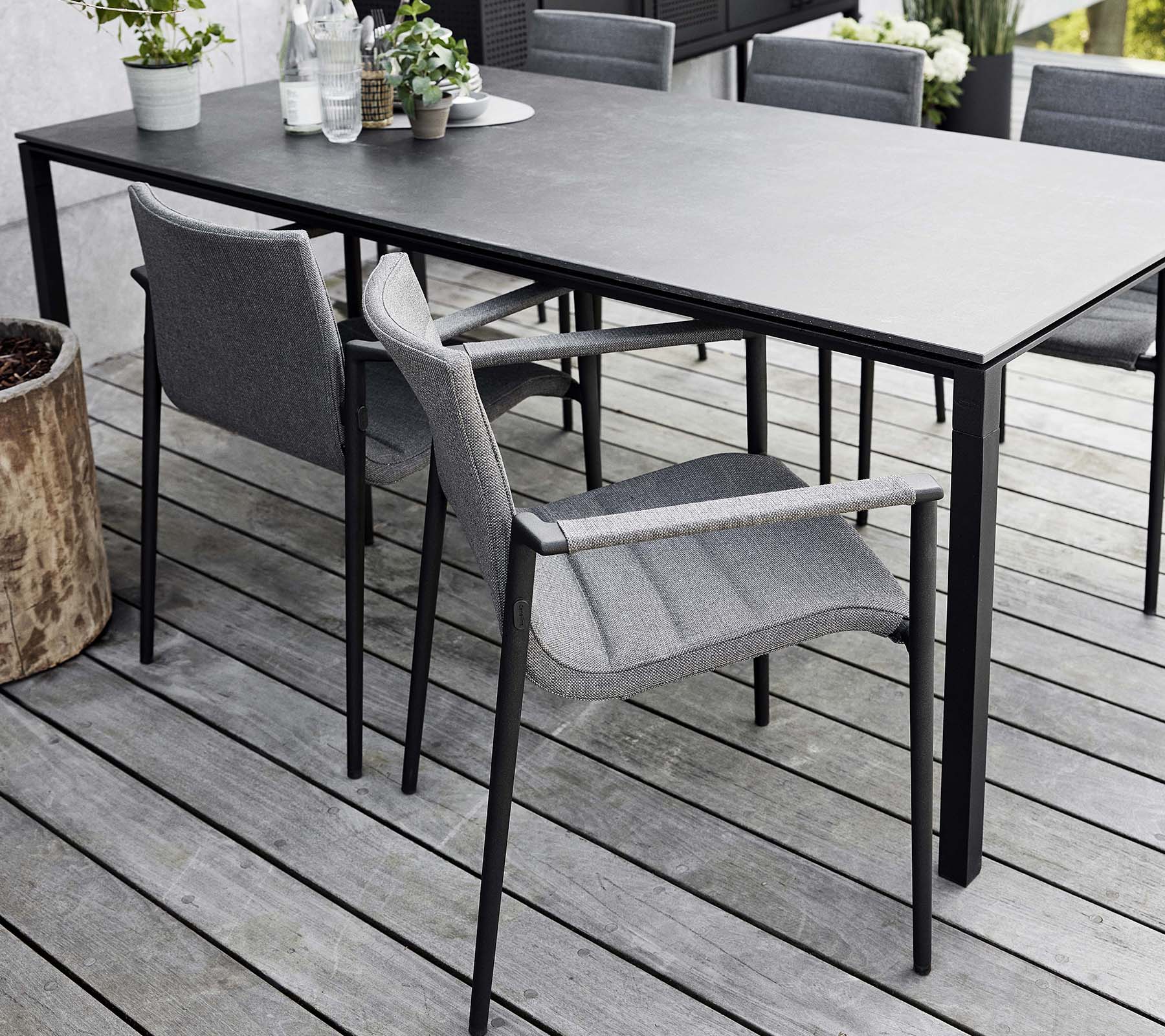 Stilfull middagoppsett med et elegant bord og moderne grå kjerne-stoler, omgitt av naturlige elementer og grønt.