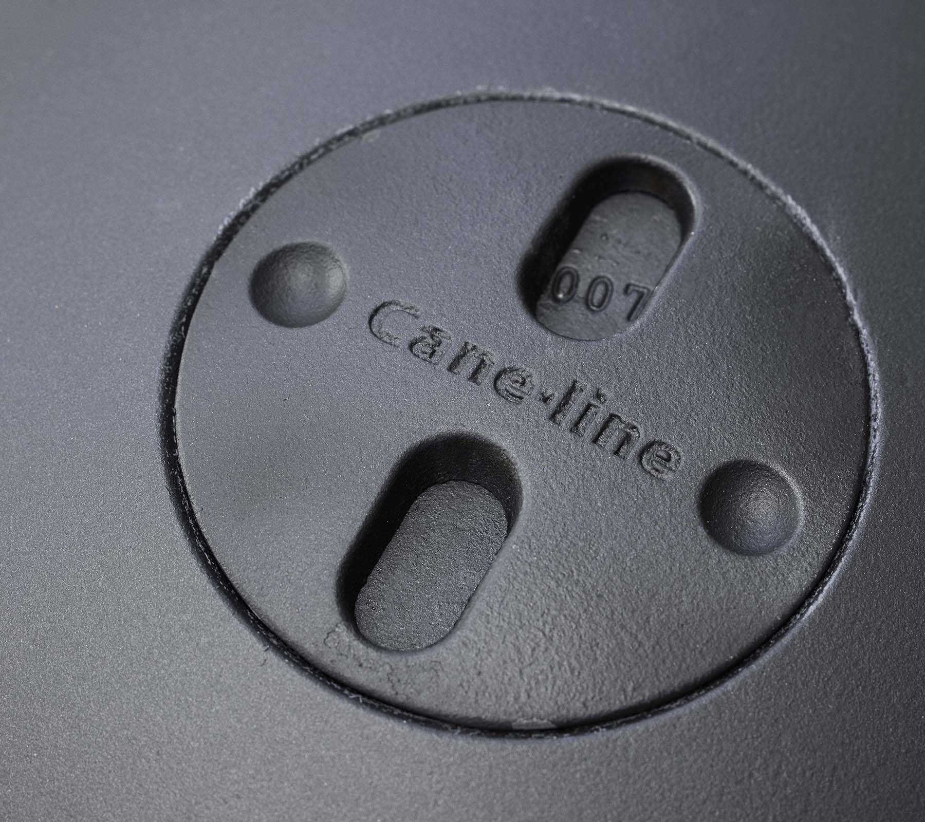 Nærbilde av et sirkulært element med graverte "Cane-line" logo og to spalter, en del av et ildsteddesign.