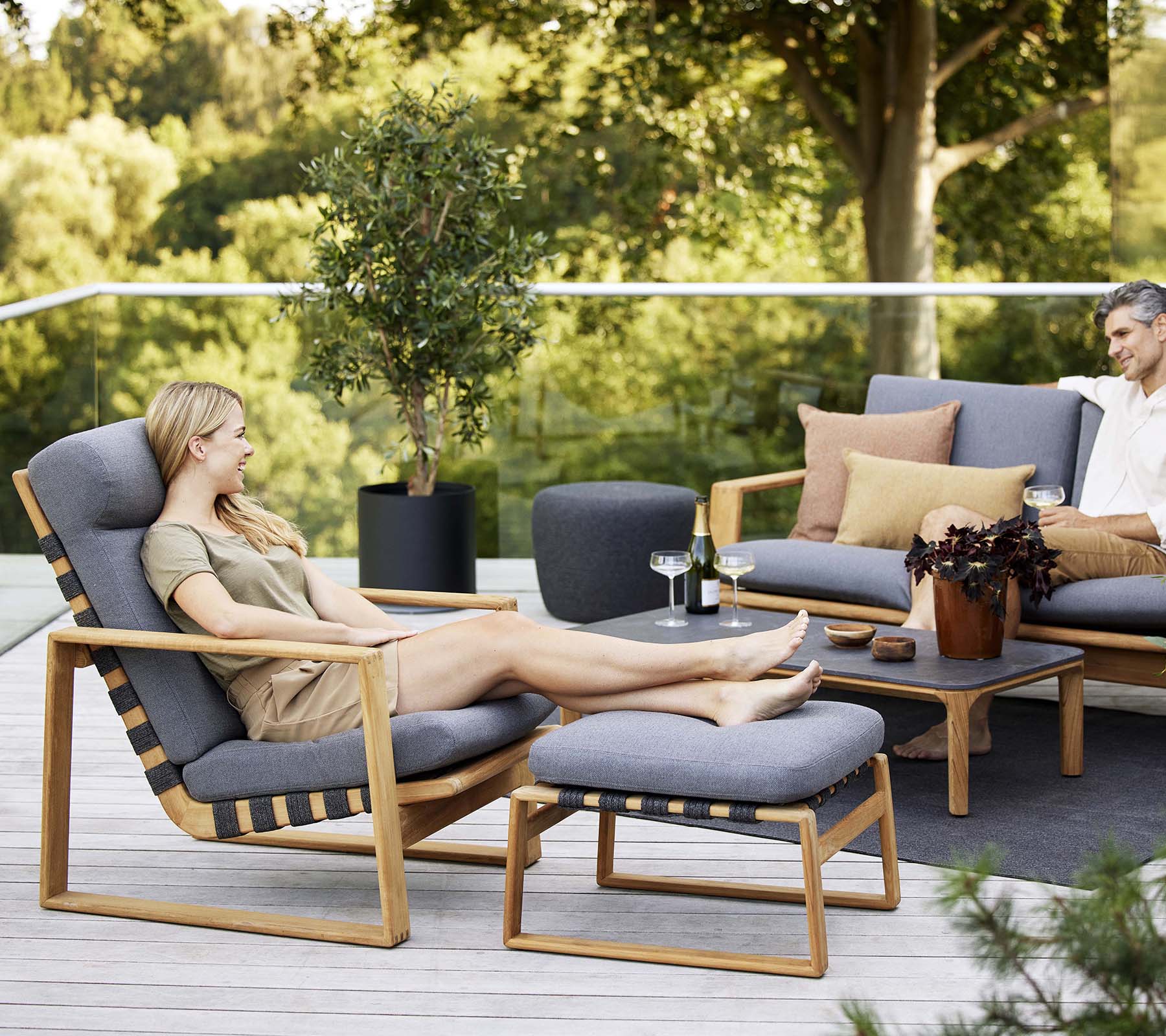 Avslappende scene med en høyrygget stol og en matchende sofa, supplert med dekorative puter og et lite bord.