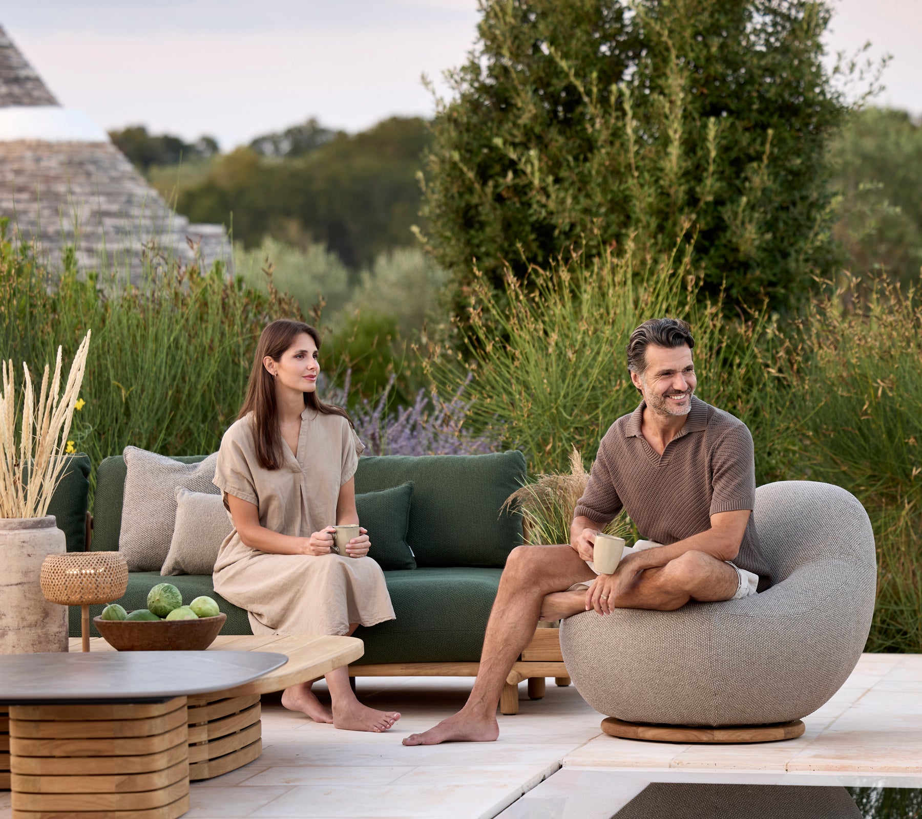 Moderne stue med grønn sofa, grå rund stol og brun bord omgitt av grønt.