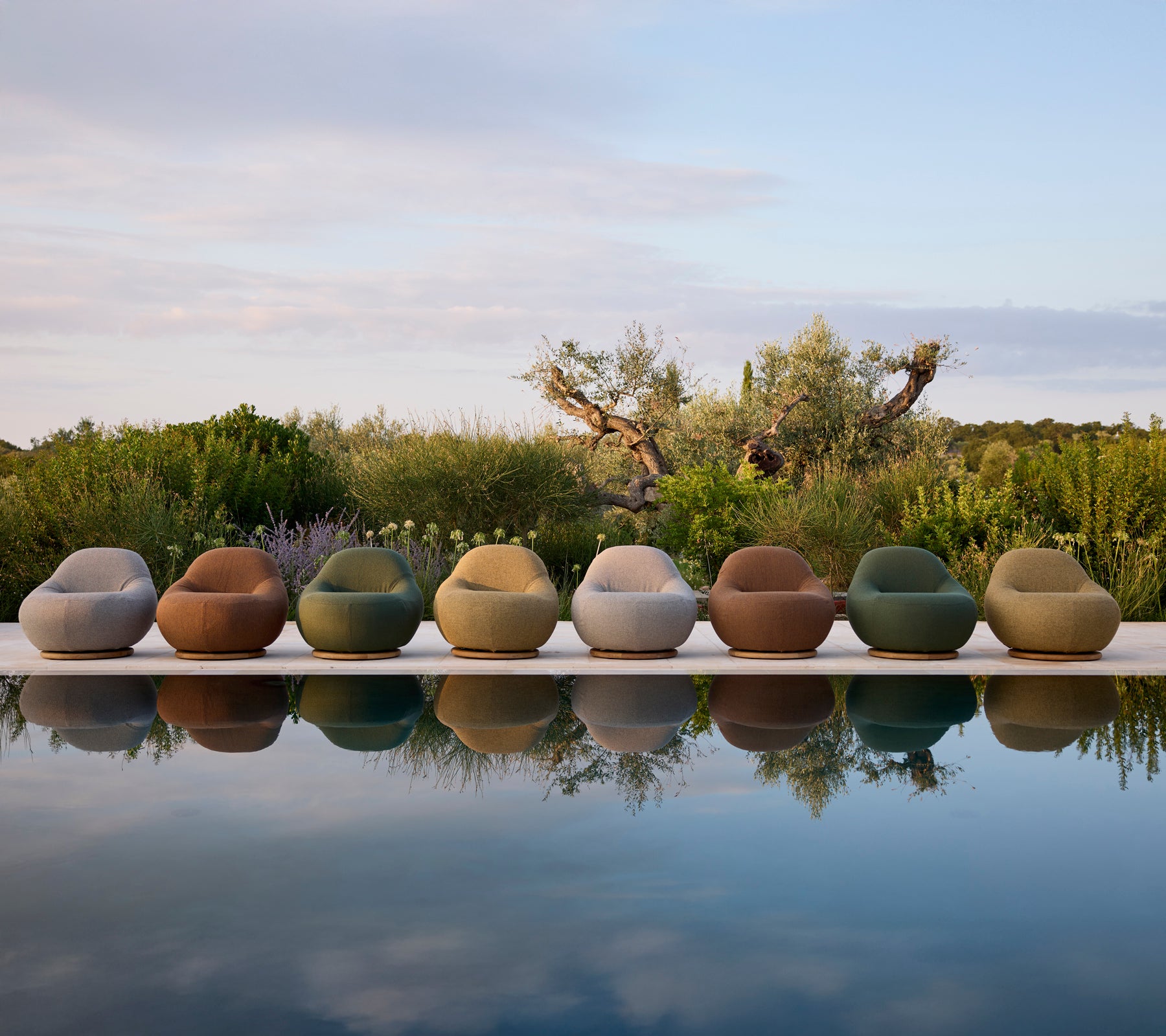 Moderne utemøbler i forskjellige farger ordnet ved svømmebassenget.