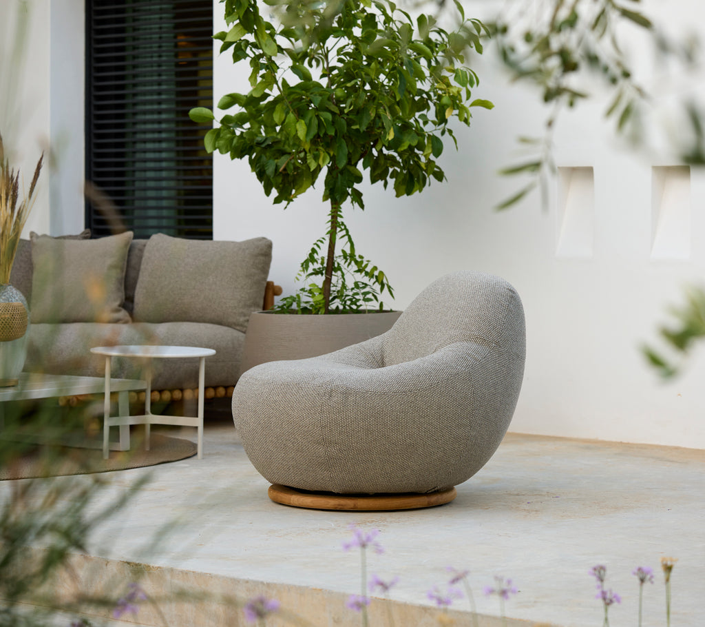 Moderne loungeinnstilling med en grå stol, grå pute og hvit bord.